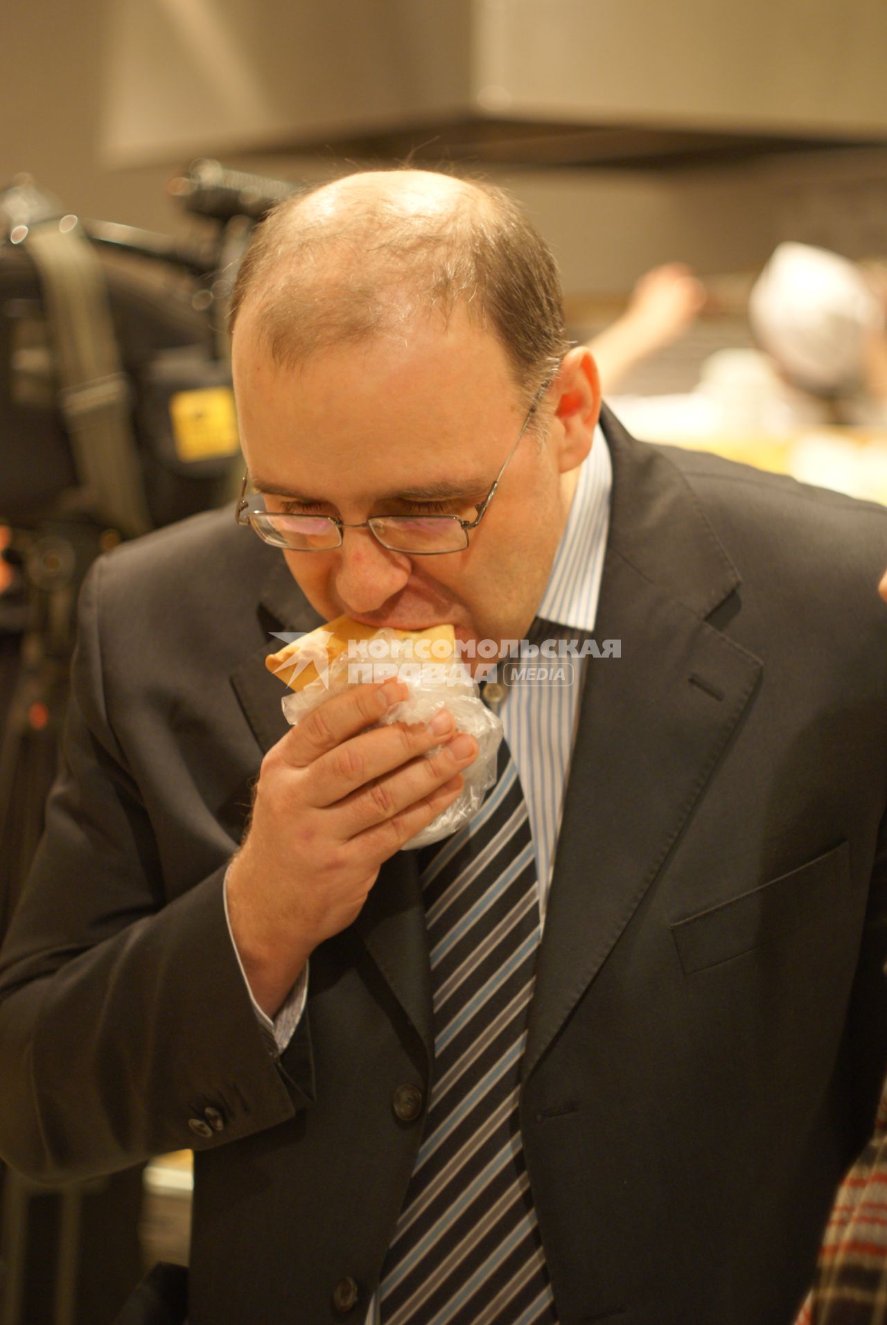 Мужчина ест булочку.