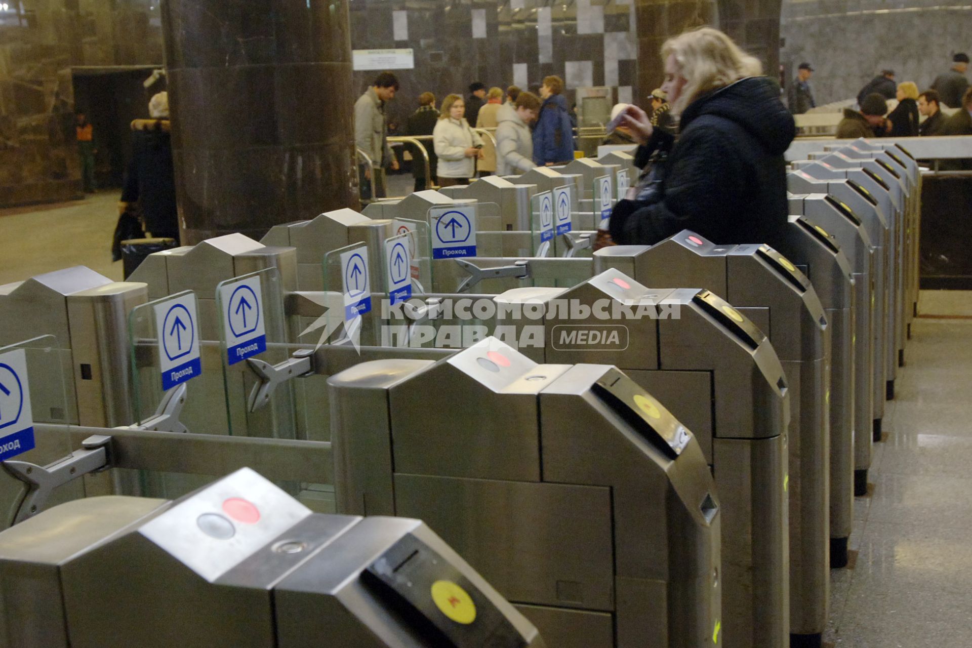 Женщина проходит через турникет в метро.