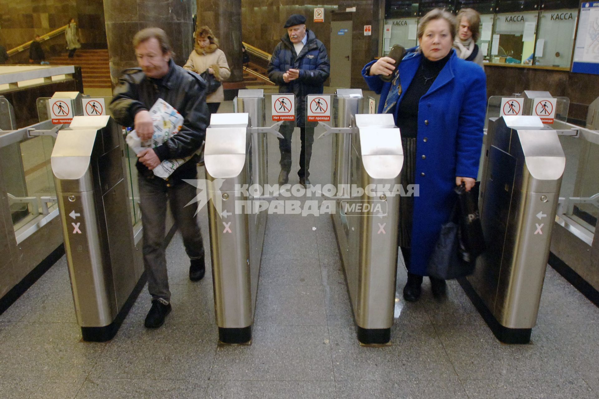 Люди проходят через турникеты в метро.