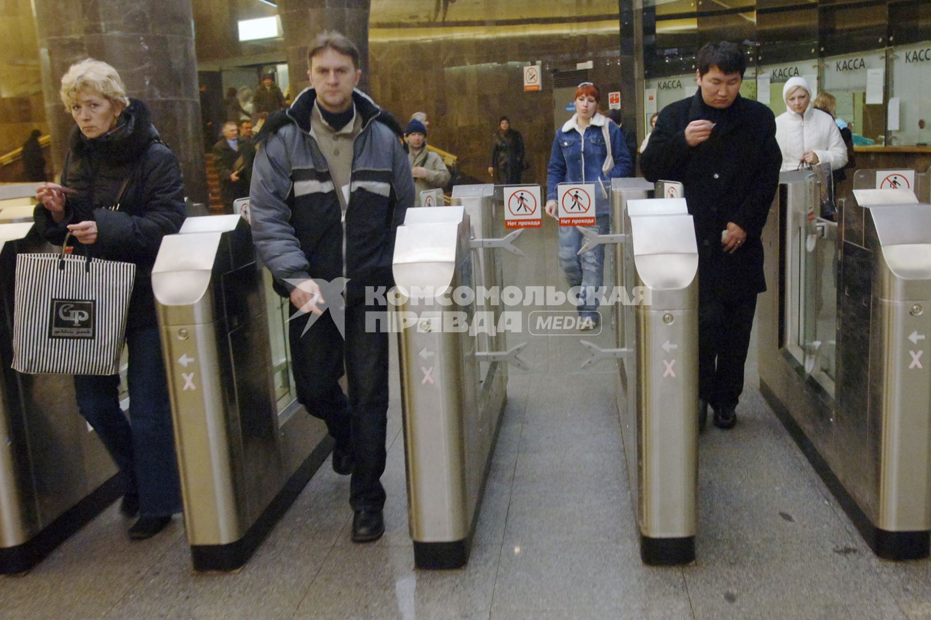 Люди проходят через турникеты в метро.