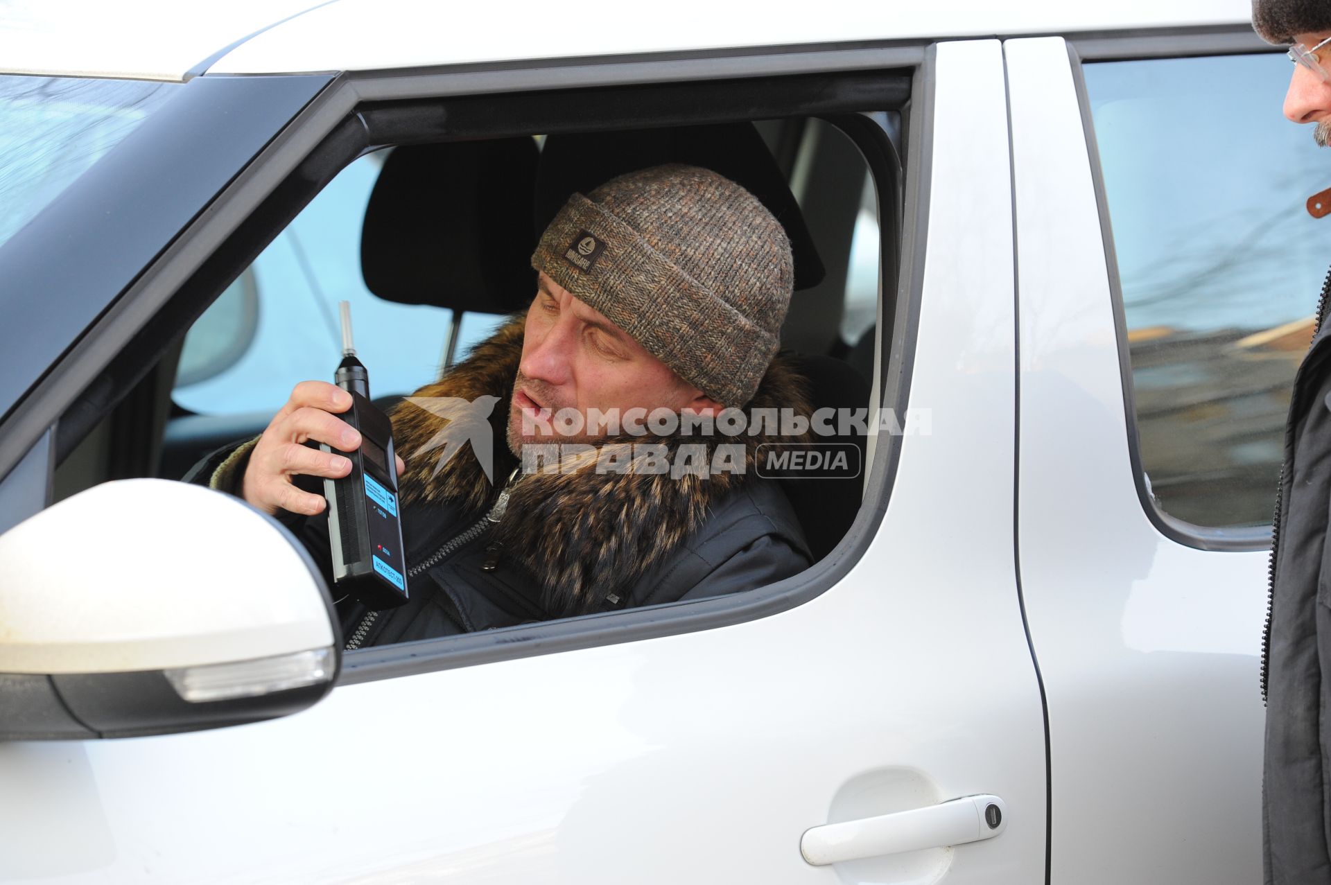 Водитель автомобиля проверяет себя на наличие алкоголя в крови.