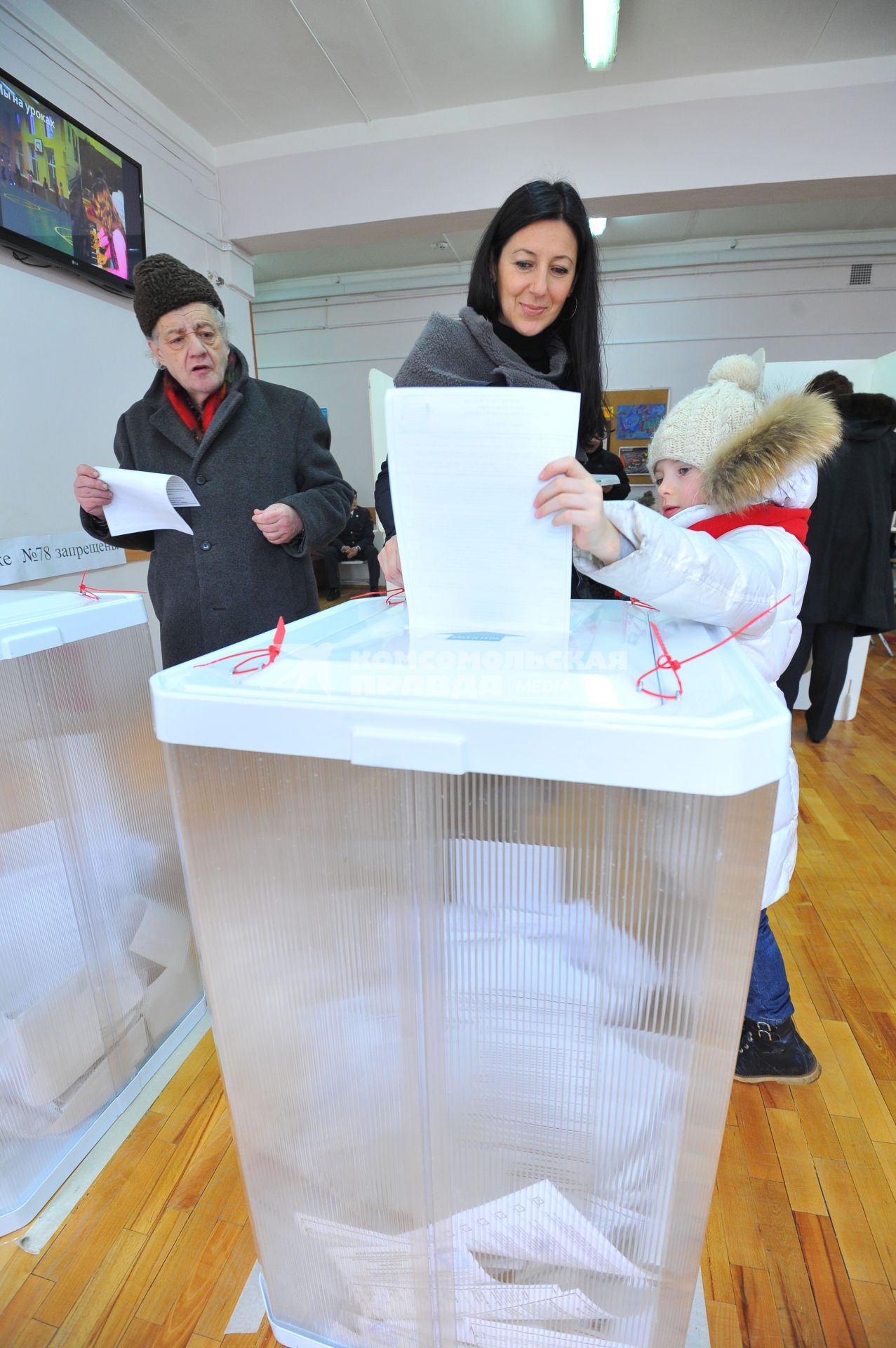 Жители Москвы опускают бюллетень во время голосования на выборах президента РФ на избирательном участке  78., Москва, 4 марта 2012 года