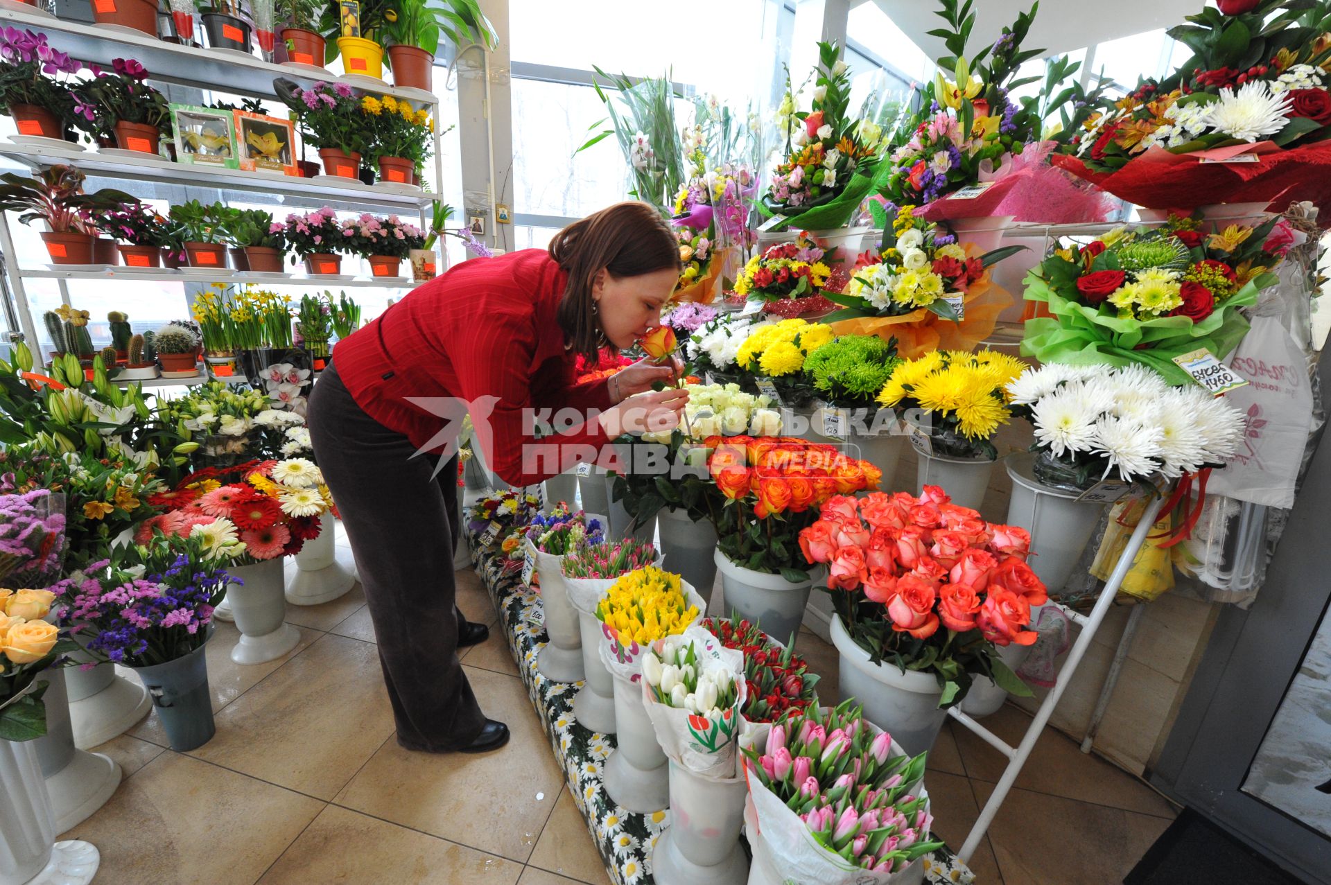 Цветочный магазин. На снимке: женщина нюхает розу.