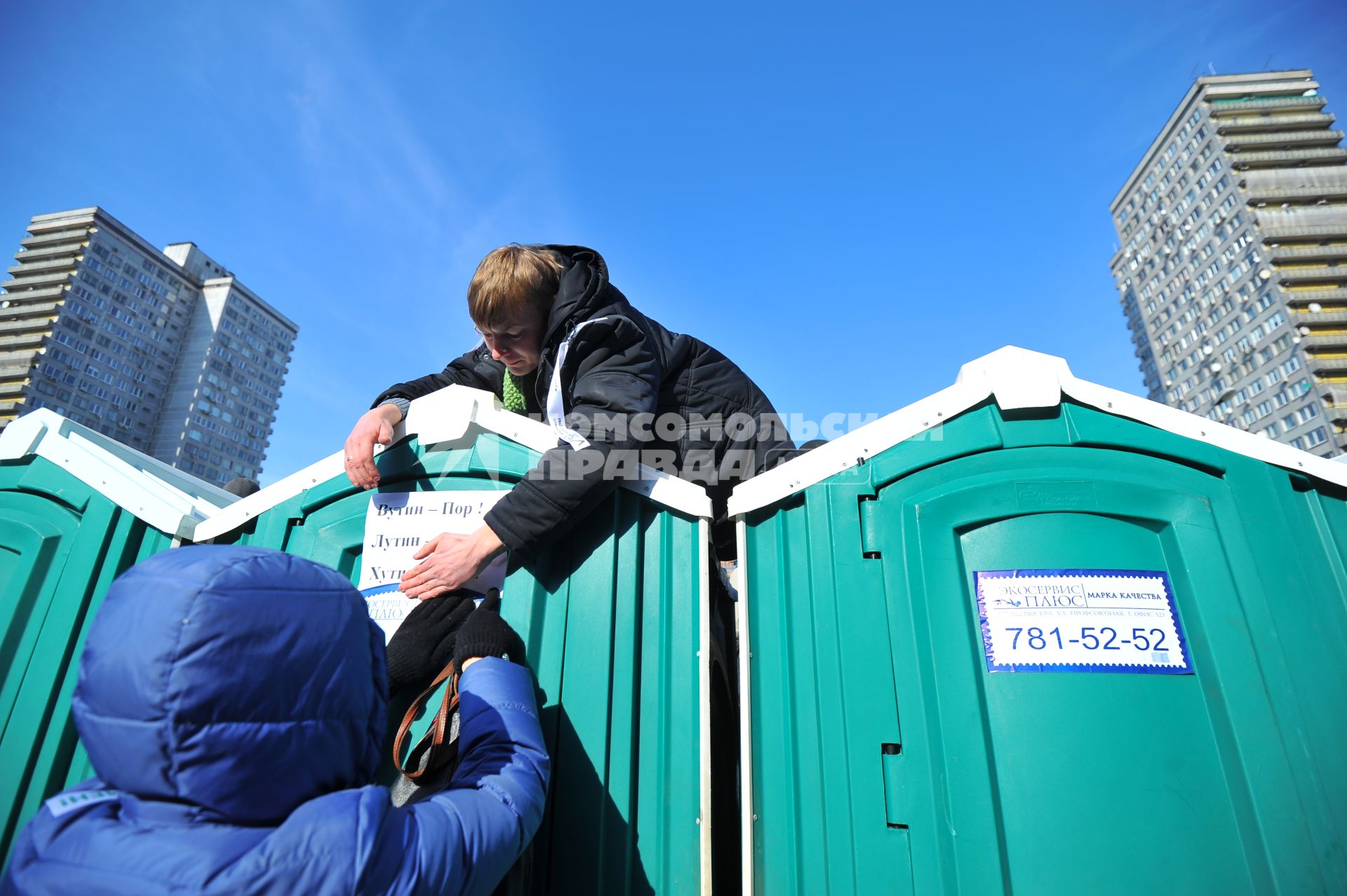 Новый Арбат. Митинг `За честные выборы`, организованный активистами движения `Левый фронт` . На снимке: участники митиинга наклеивают лист с надписью протеста на кабинку общественного туалета.