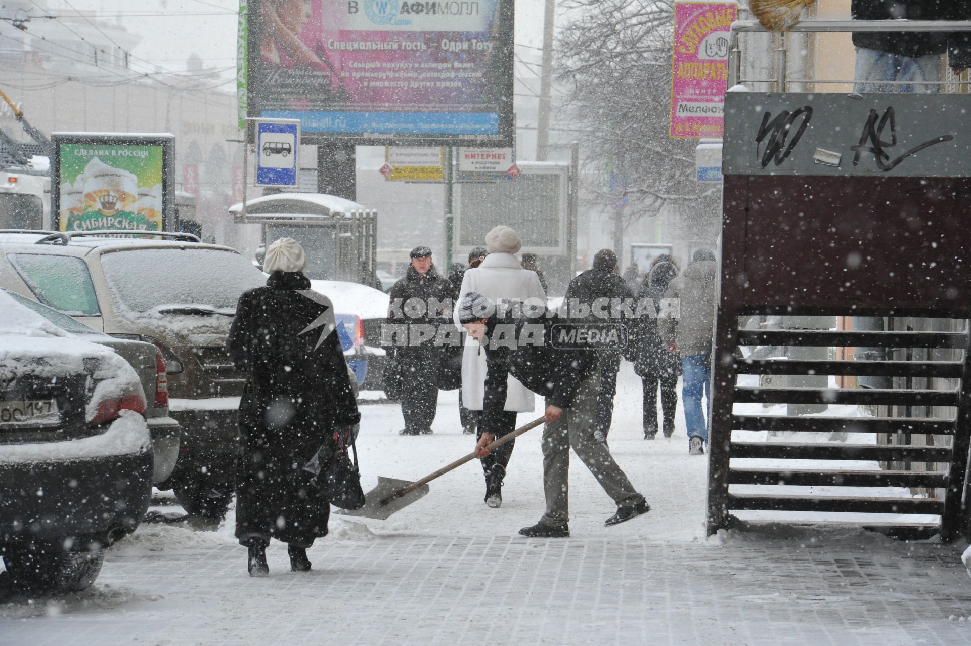 Снегопад в городе.  На снимке: гастарбайтер убирает лопатой снег с тротуара.