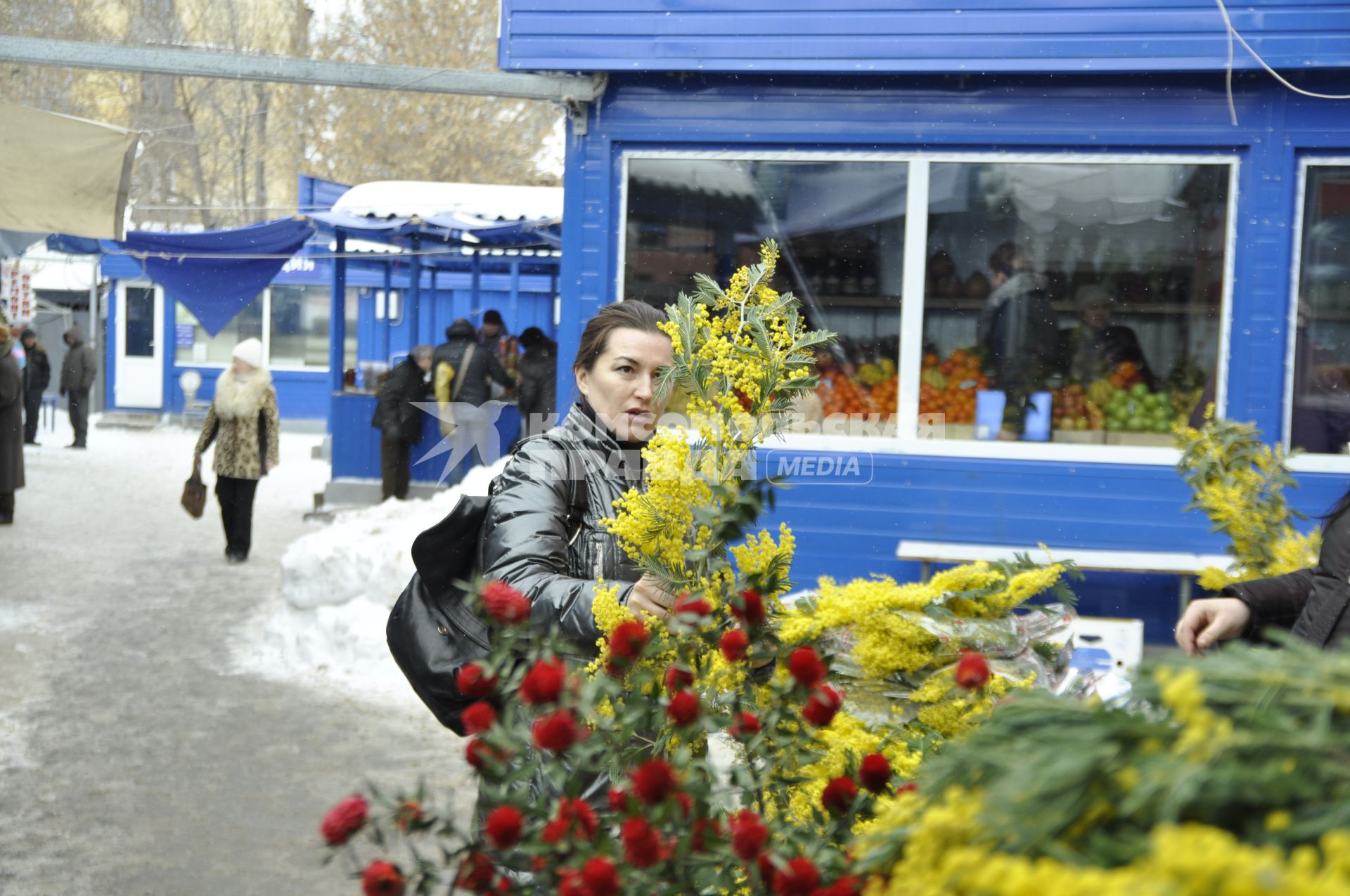 Девушка выбирает букет мимоз.