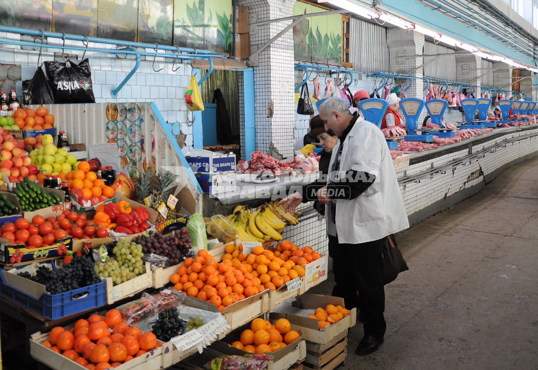 Продавец фруктов показывает покупателю товар.
