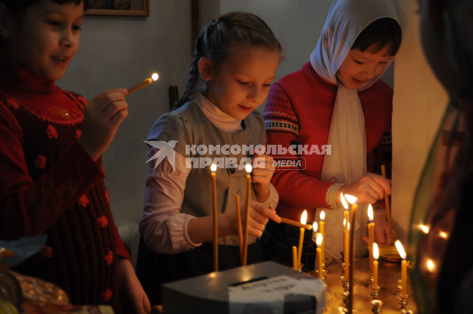 Девочки зажигают свечи в церкви.