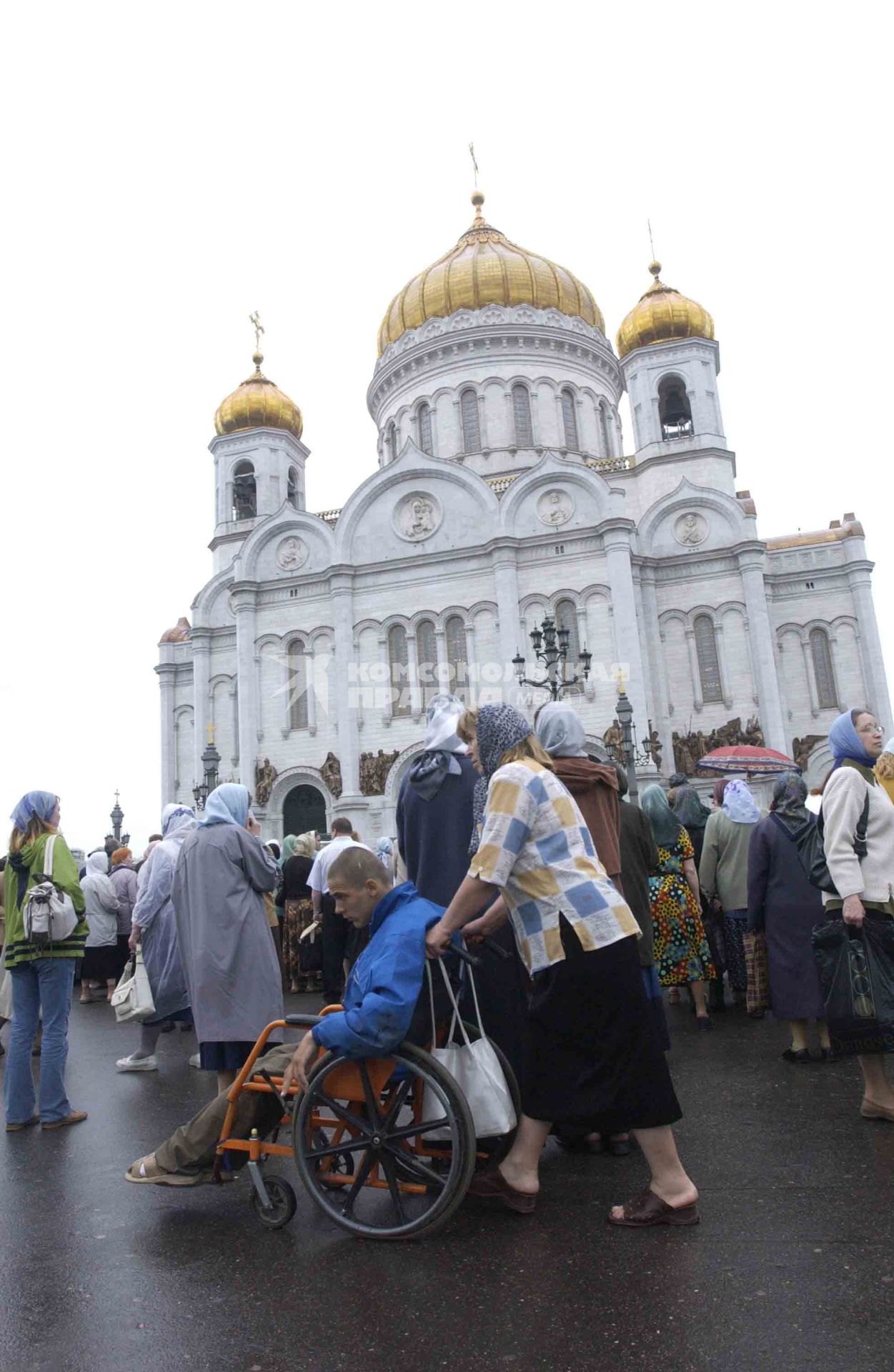 Верующие в очереди к золотому ковчегу со стопой первого ученика Иисуса Христа святого апостола Андрея Первозванного, доставленному в храм Христа Спасителя. Мать с сыном-нивалидом на коляске.