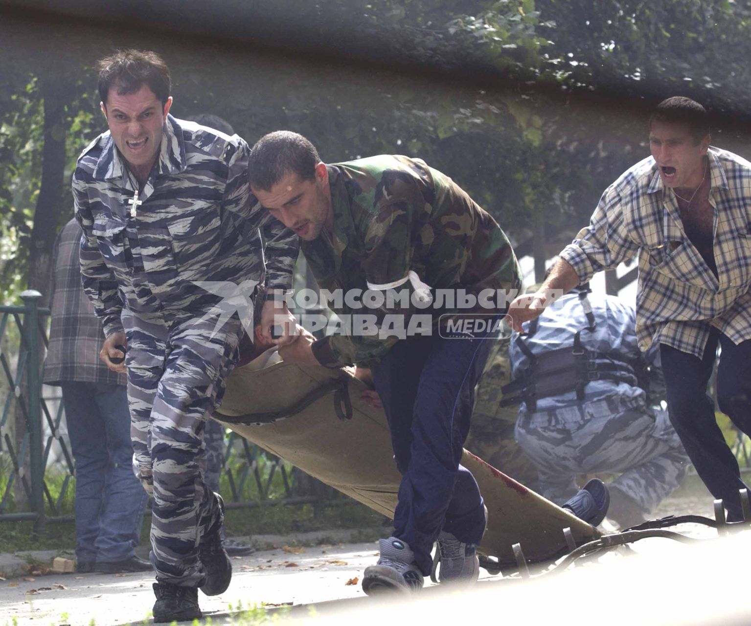 Захват заложников террористами в школе   1 города Беслан. Мужчины тащут на носилках раненого.