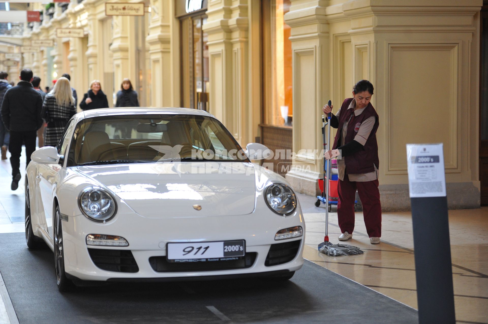 ГУМ. Выставка уникальных автомобилей Porsche, расположенных вдоль первой линии магазина, которая была временно стилизована под `Улицу Porsche`.На снимке: уборщица и автомобиль Porsche.