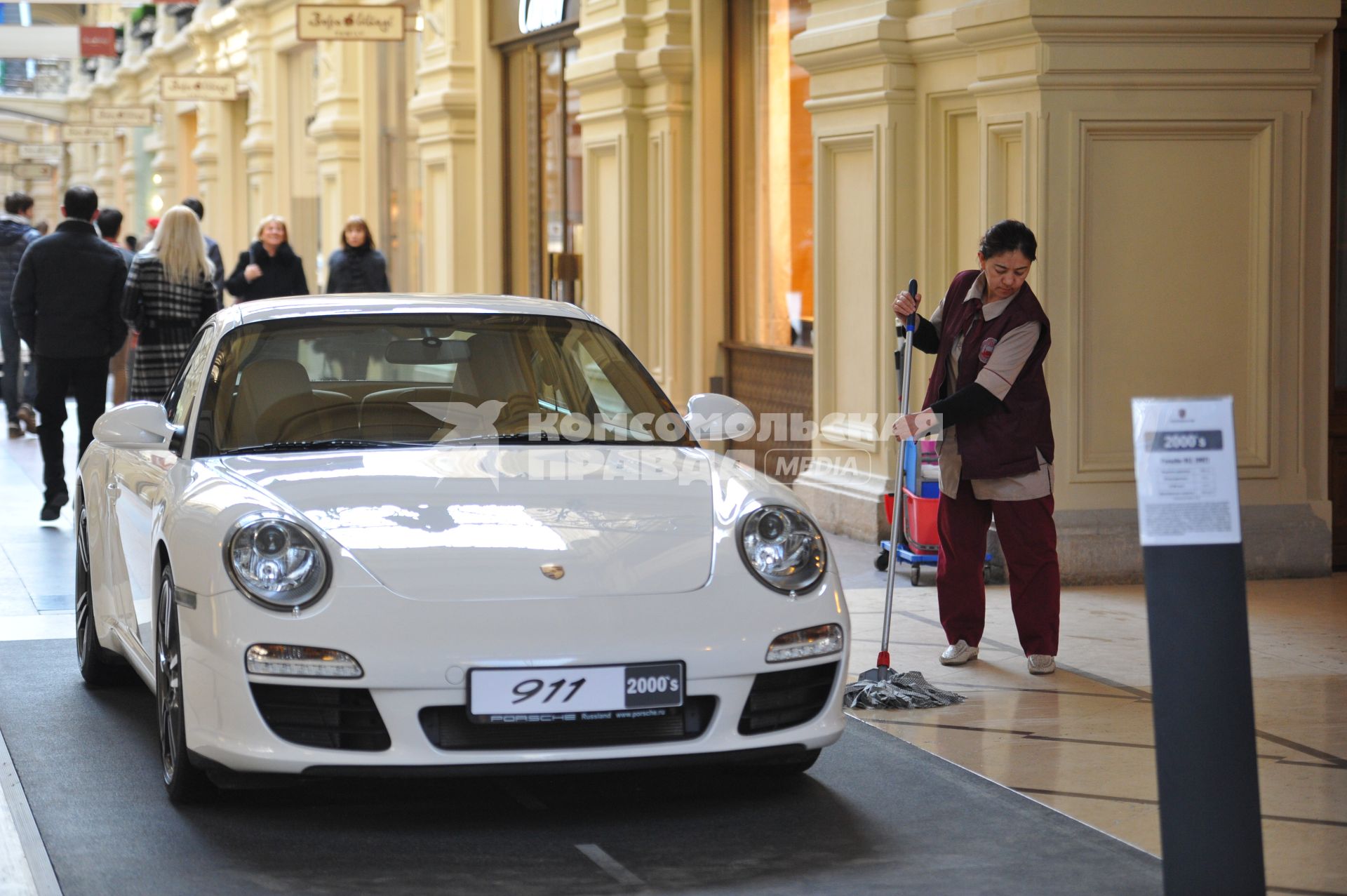 ГУМ. Выставка уникальных автомобилей Porsche, расположенных вдоль первой линии магазина, которая была временно стилизована под `Улицу Porsche`.На снимке: уборщица и автомобиль Porsche.