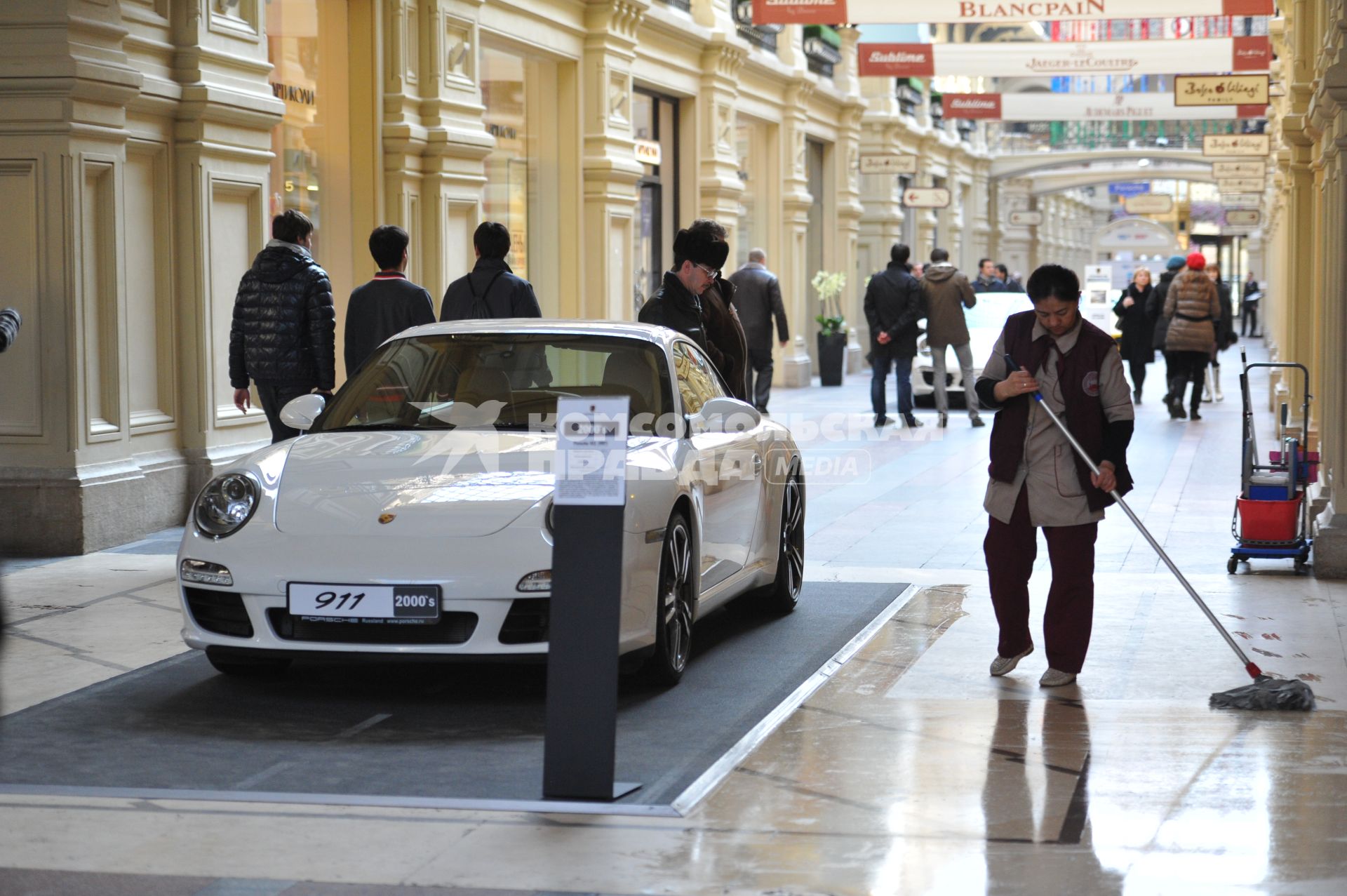 ГУМ. Выставка уникальных автомобилей Porsche, расположенных вдоль первой линии магазина, которая была временно стилизована под `Улицу Porsche`.На снимке: уборщица и автомобиль Porsche.