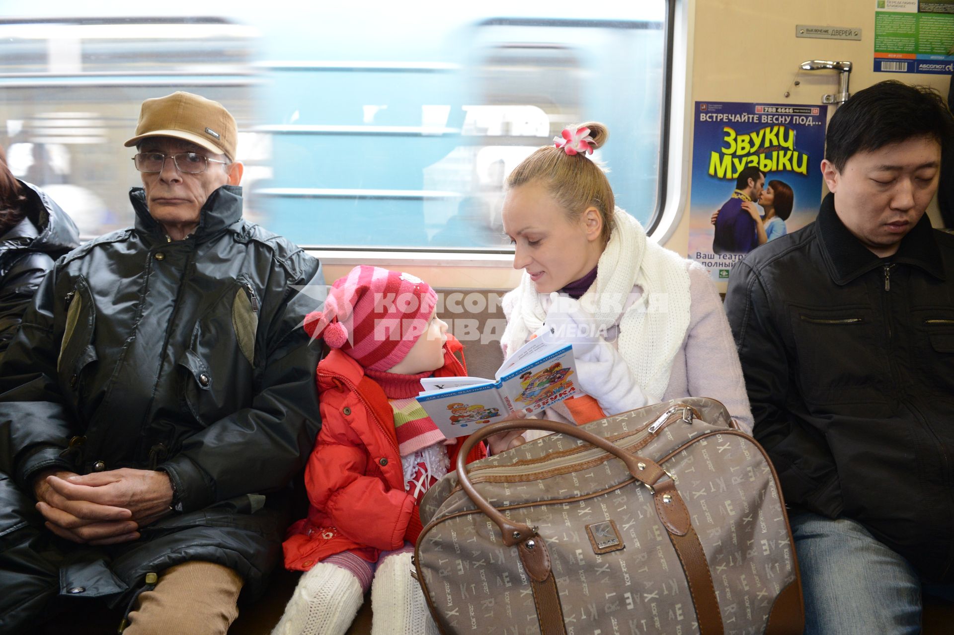 Мать дочери  читает книгу во время поездки в метро.