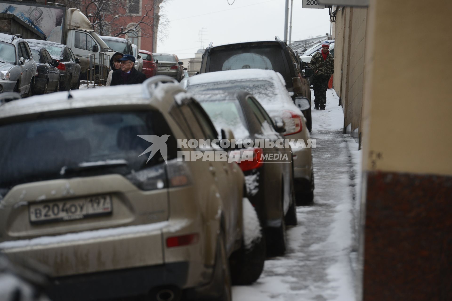 Припаркованные автомобили и пешеходы на городской улице.