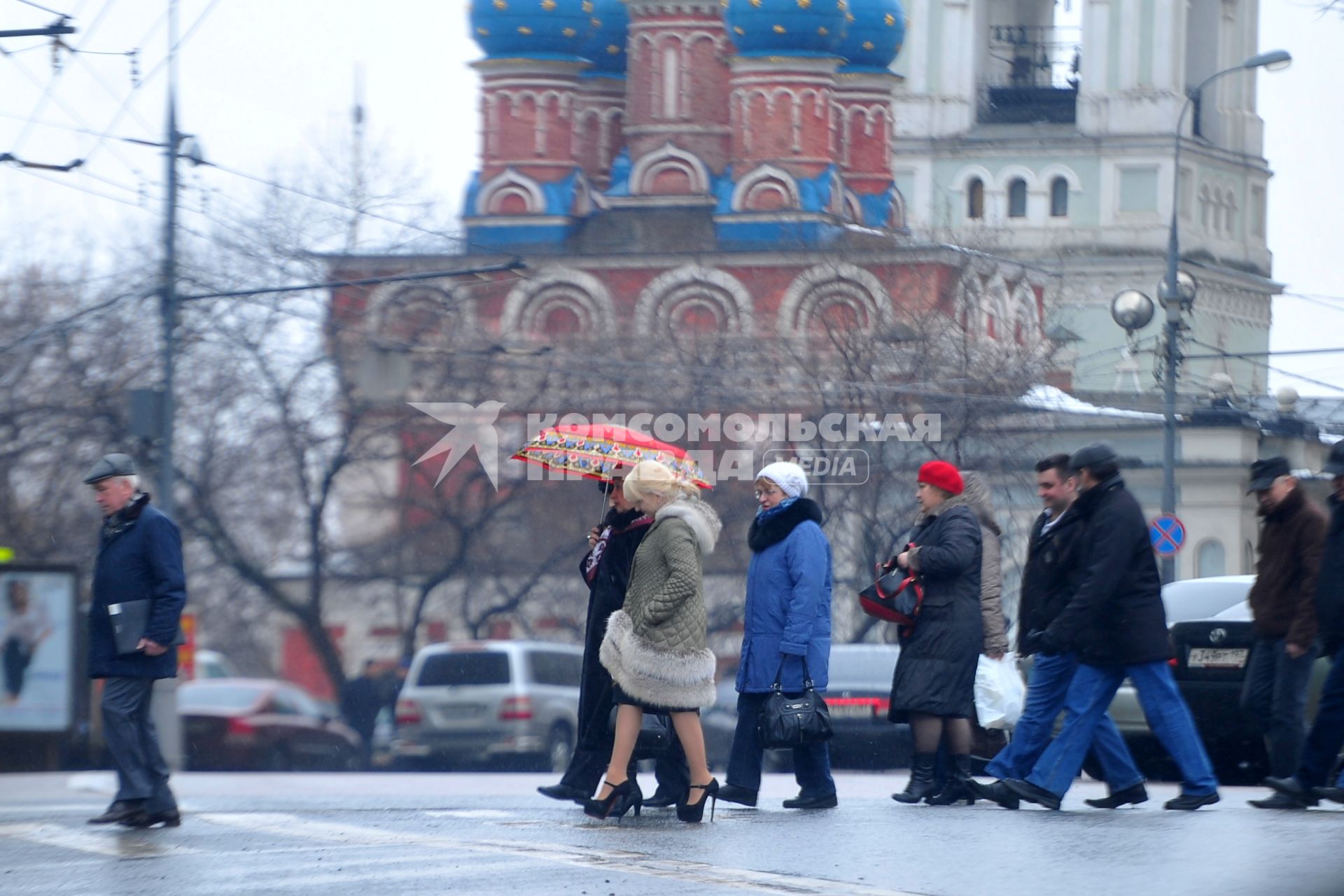 Люди переходят дорогу по пешеходному переходу.