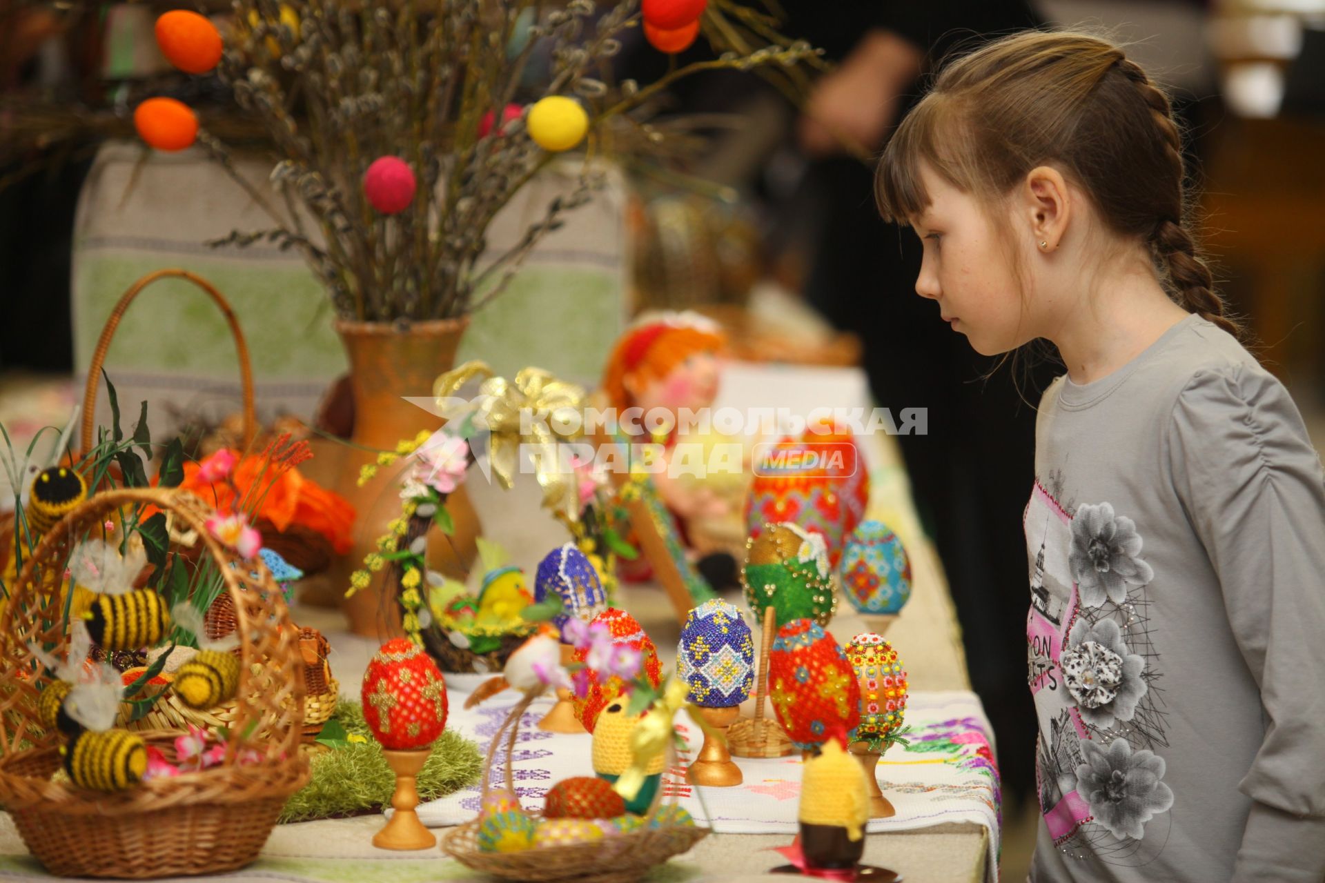 Девочка рассматривает украшенный пасхальные яйца.