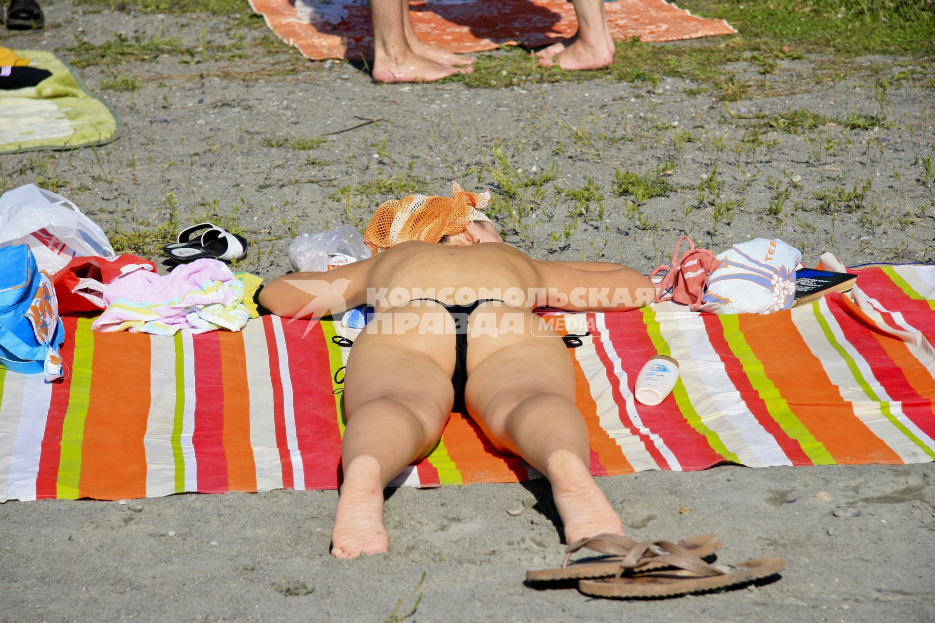 Девушка загорает на пляже без купальника.