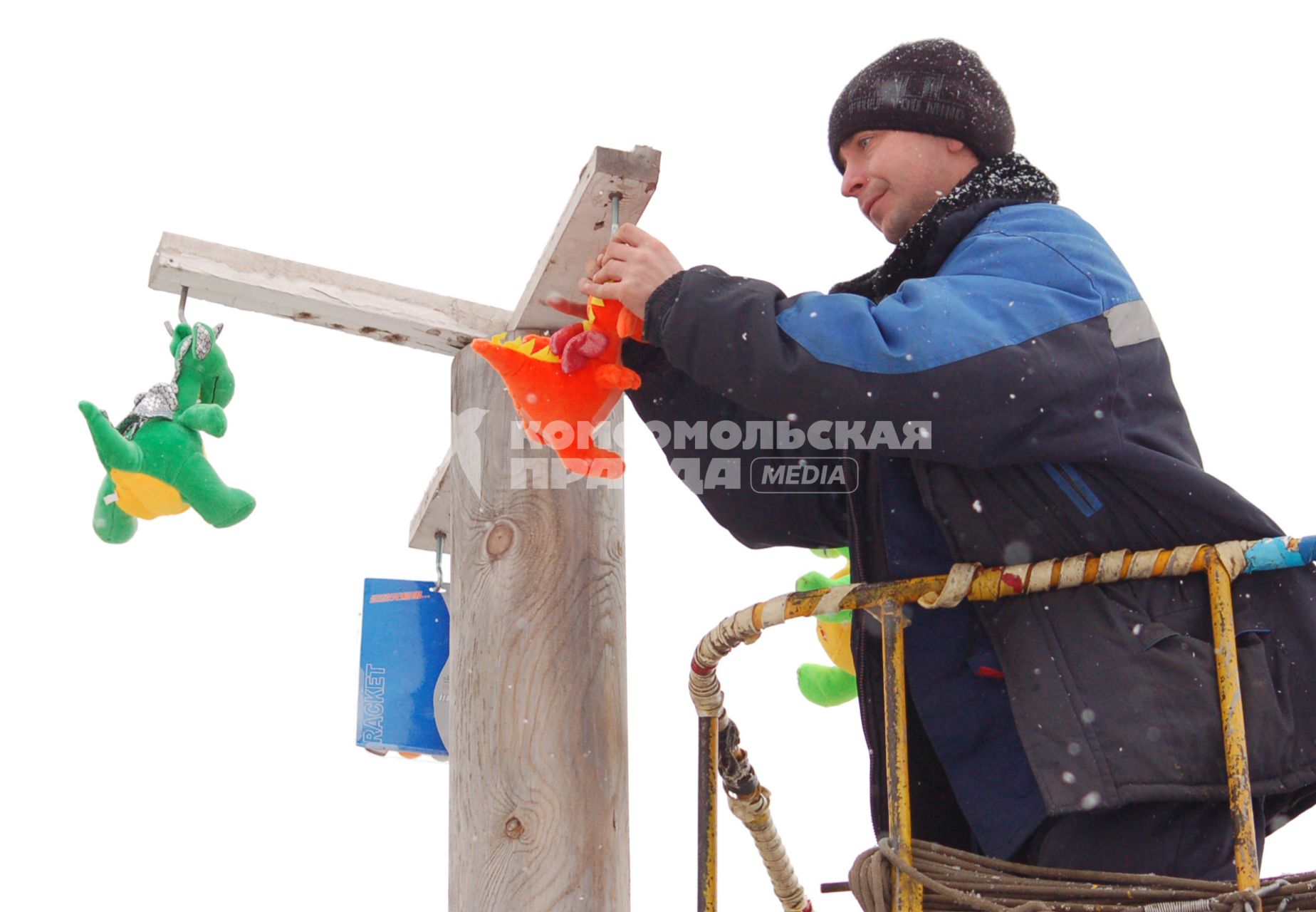 Мужчина развешивает игрушки на ледяном столбе для конкурса.