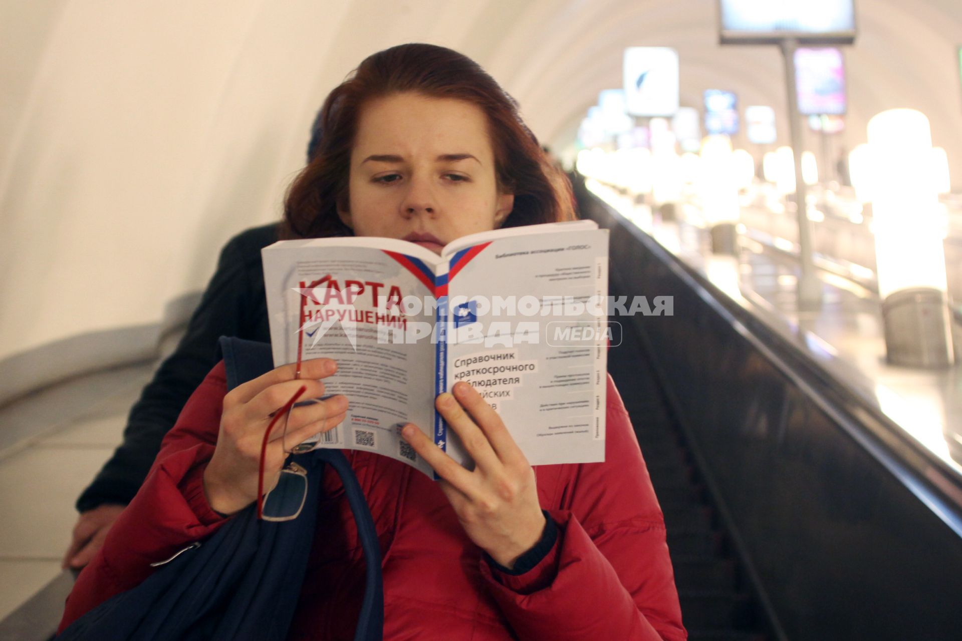 Девушка в метро читает книгу на которой написано: `Карта нарушений`.