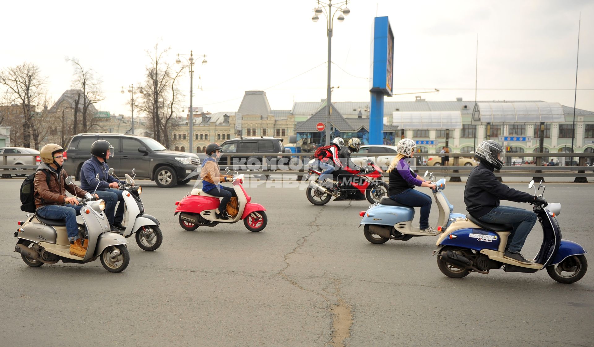 Молодежь едет на скутерах и мопедах по городу.