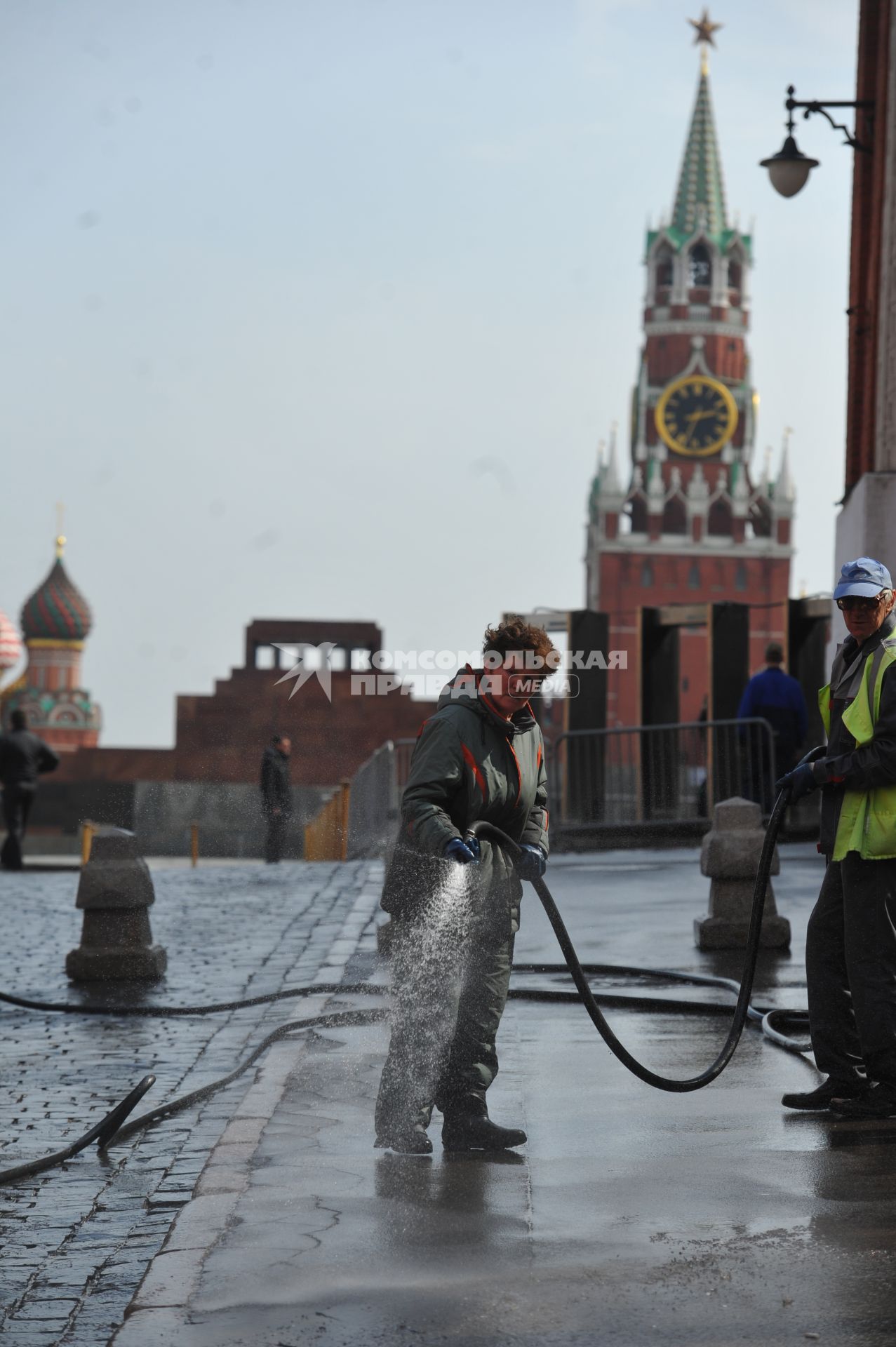 Красная площадь.  На снимке: женщина моет из шланга брусчатку и тротуар.