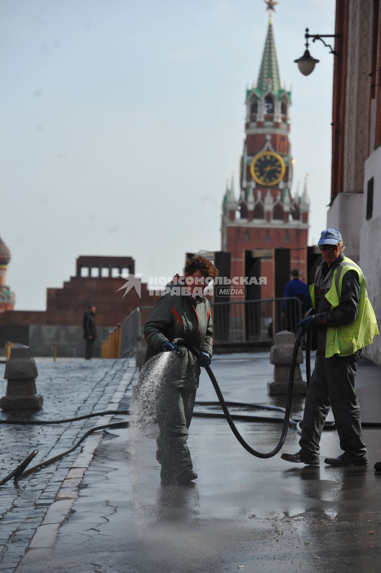 Красная площадь.  На снимке: женщина моет из шланга брусчатку и тротуар.