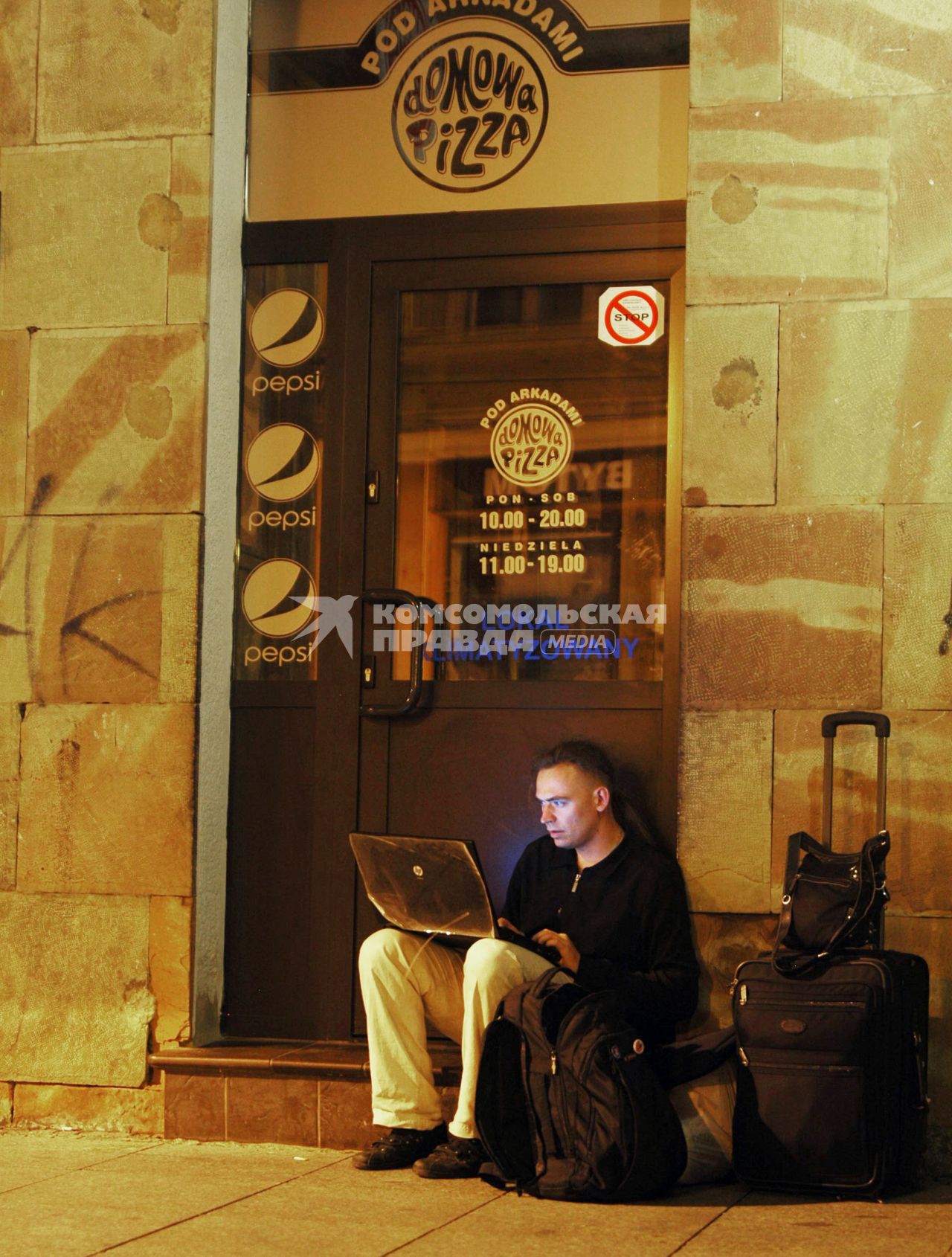 Мужчина с ноутбуком сидит около кафе и использует бесплатный интернет.