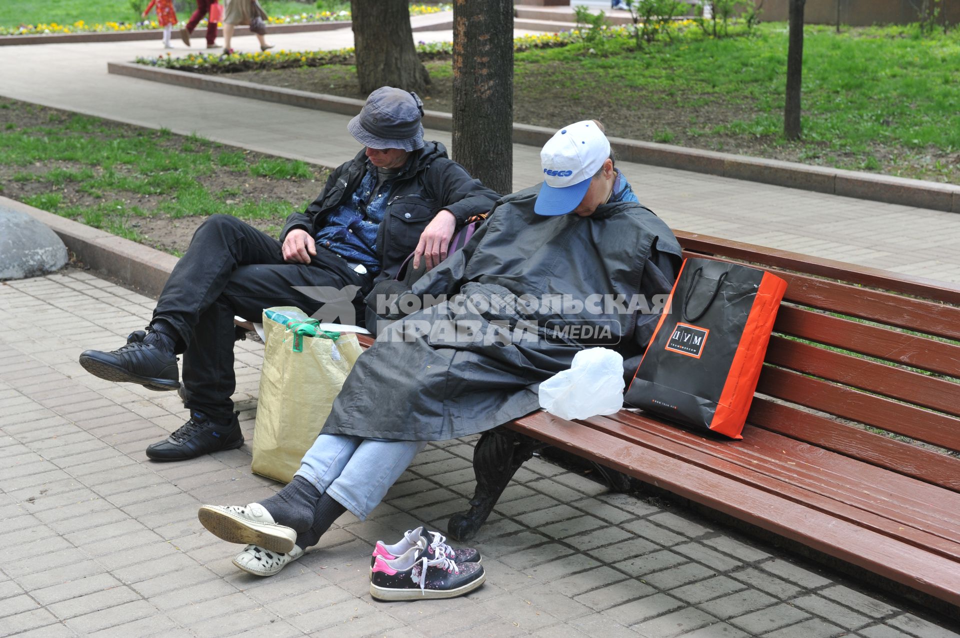 Усталость. На снимке: мужчина и женщина спят на лавочке в городском сквере.