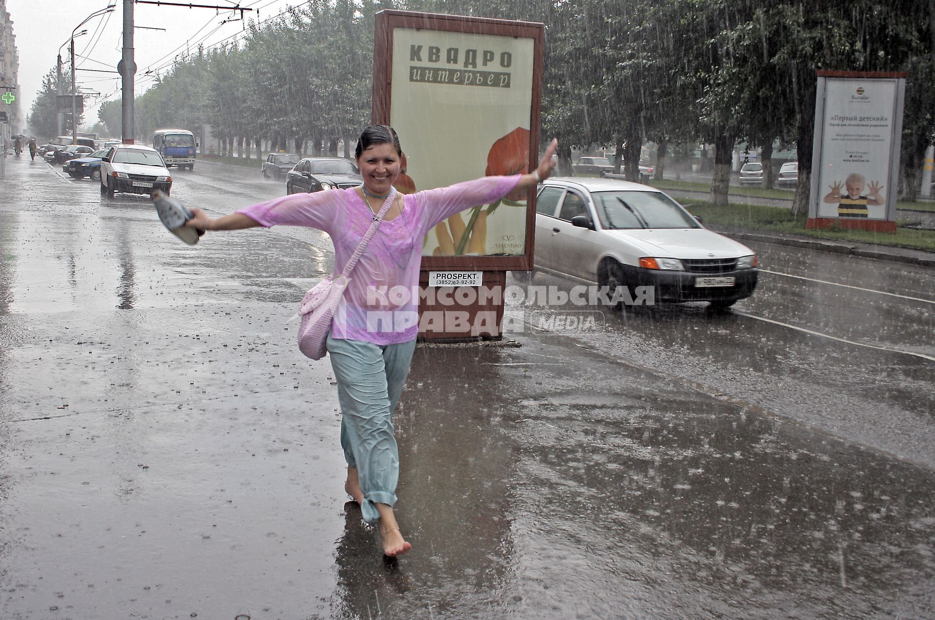 Девушка идет босиком по улице города под проливным дождем без зонта.