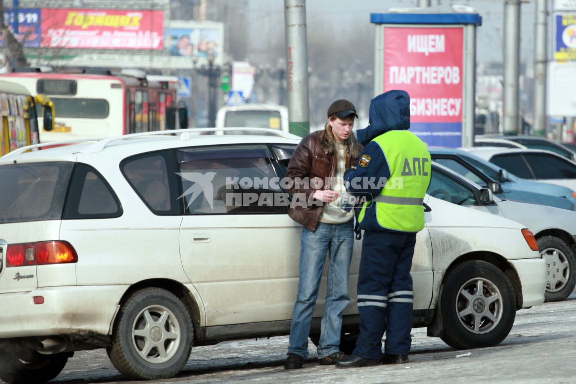 Инспектор ДПС на дороге проверяет у водителя документы.