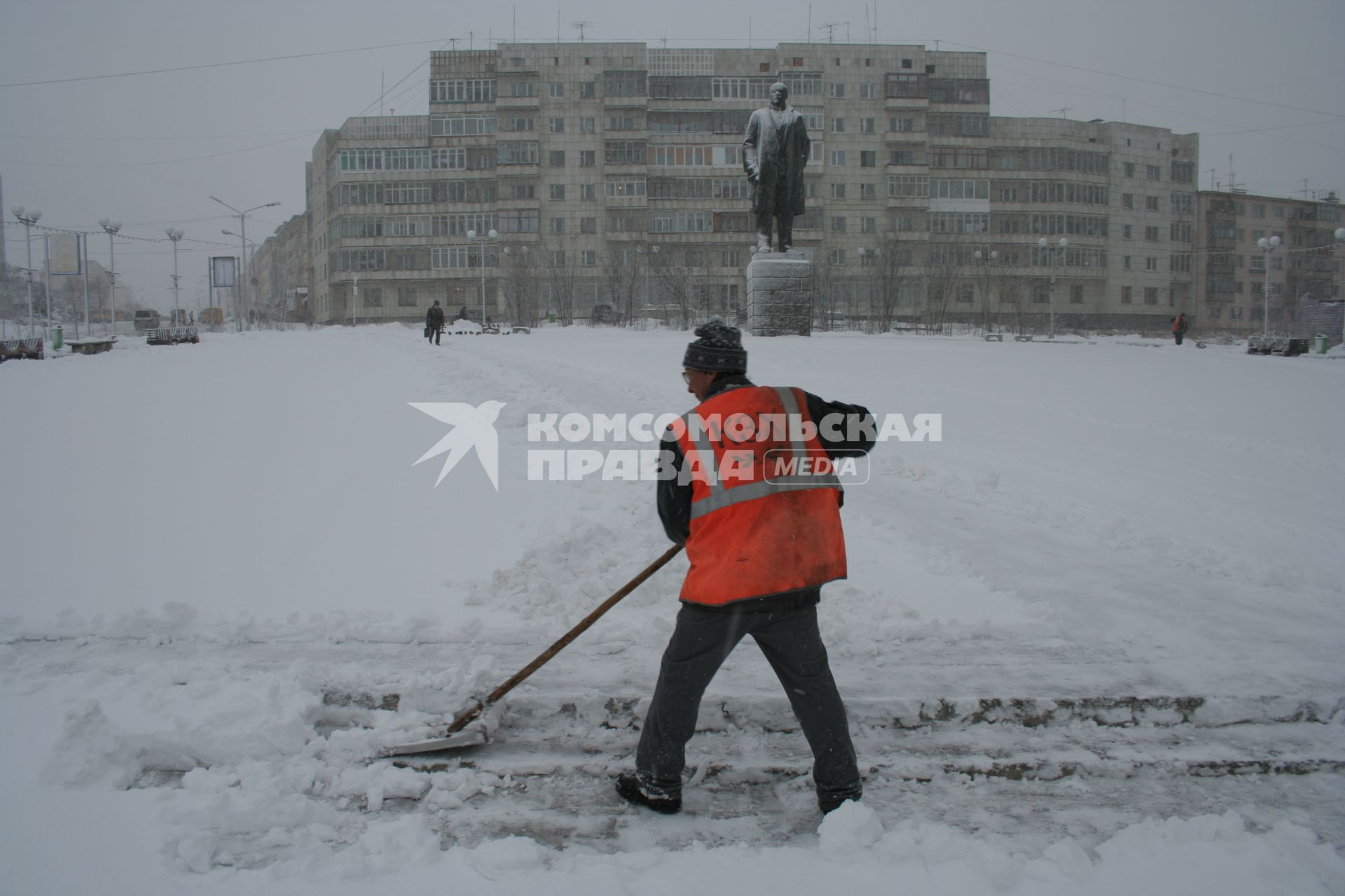 Виды Магадана. На снимке: дворник расчищает снег на площади города.