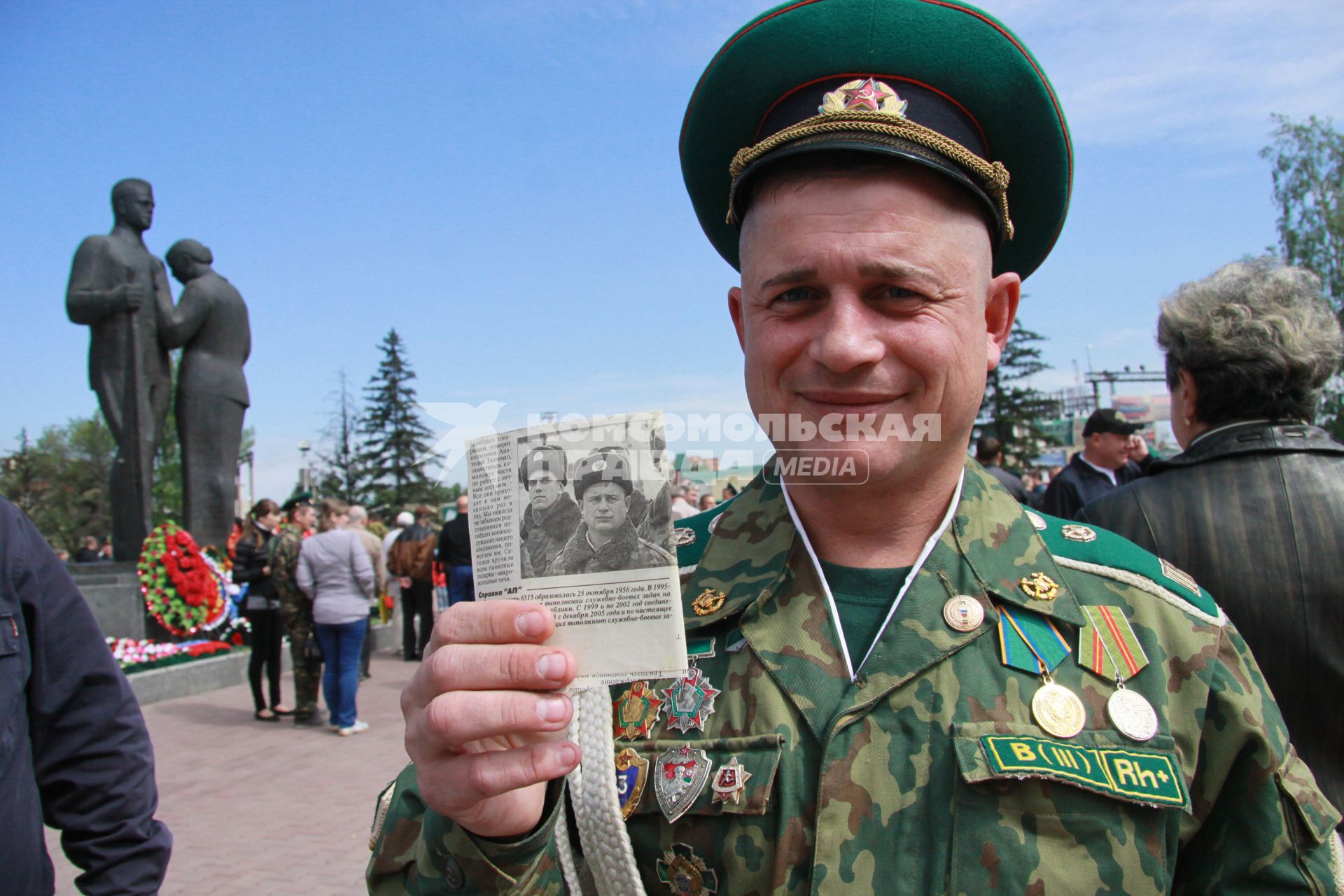 Пограничник с наградами показывает вырезку из газеты со своей фотографией.