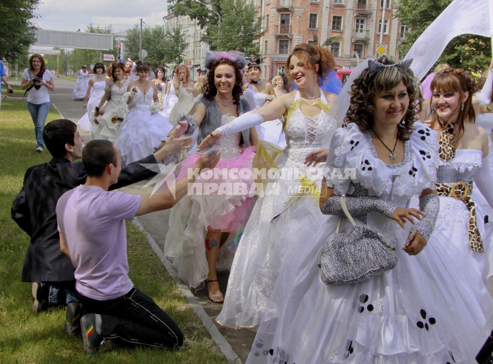 Мужчины приветствуют участниц парада невест стоя на коленях.