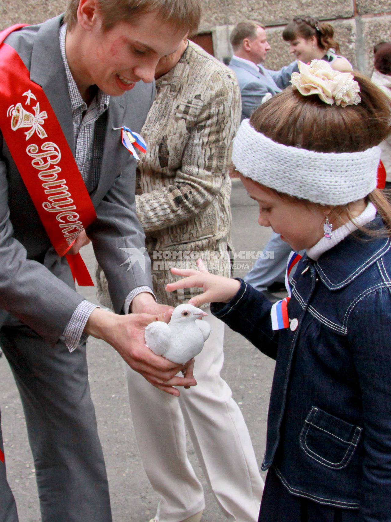Молодой человек показывает девочке белого голубя.