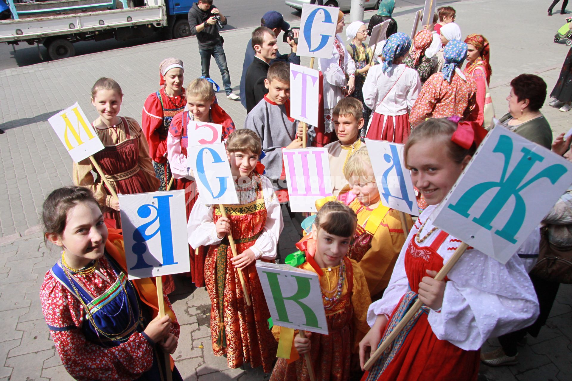 Дети в национальных русских одеждах с буквами алфавита в руках.