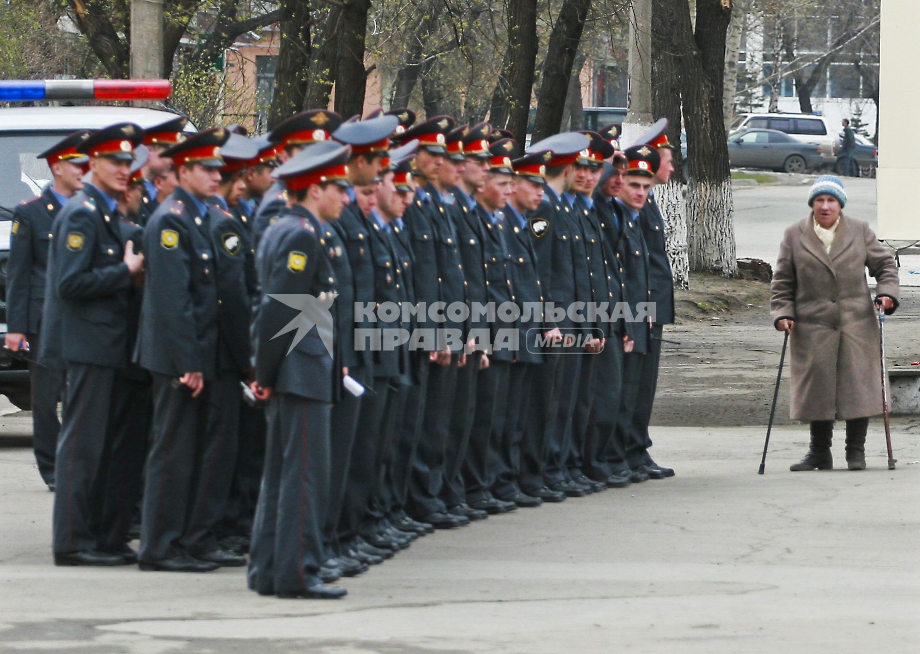 Строй милиционеров (полицейских) и бабушка на костылях.