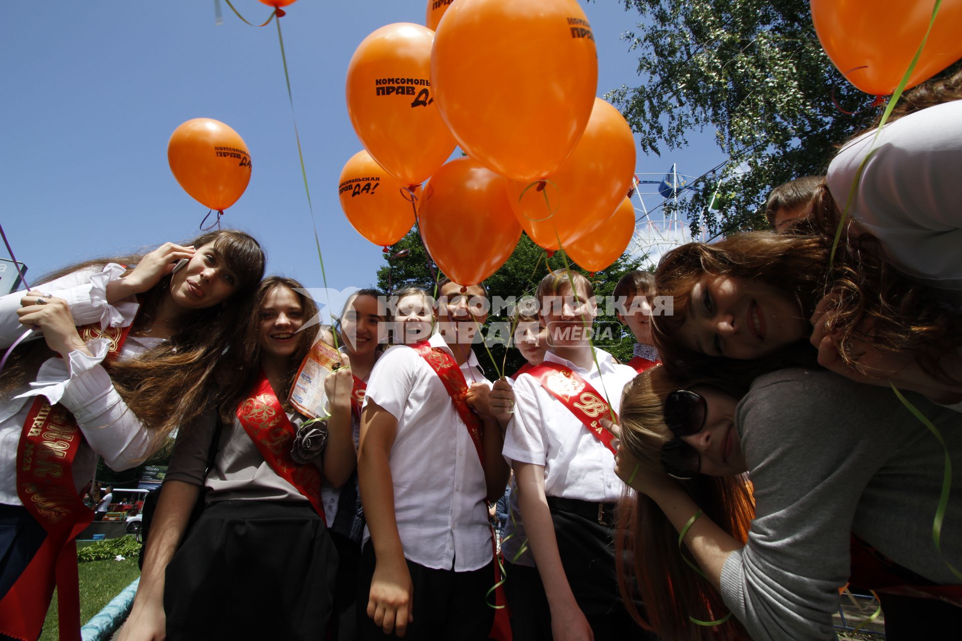 Выпускники держат воздушные шары с логотипом газеты `Комсомольская правда`.