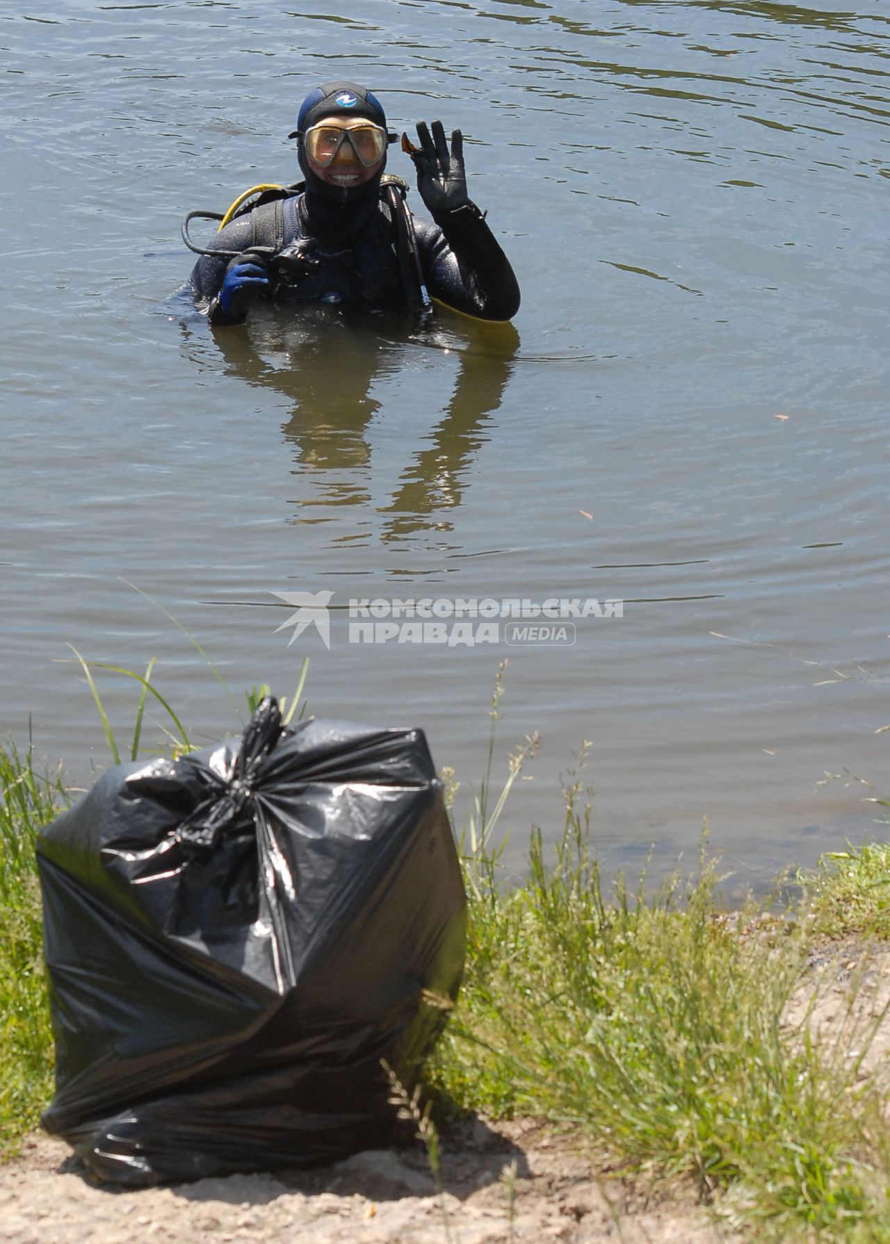 Очистка дна пруда от мусора. Аквалангист извлекает со дна мусор.