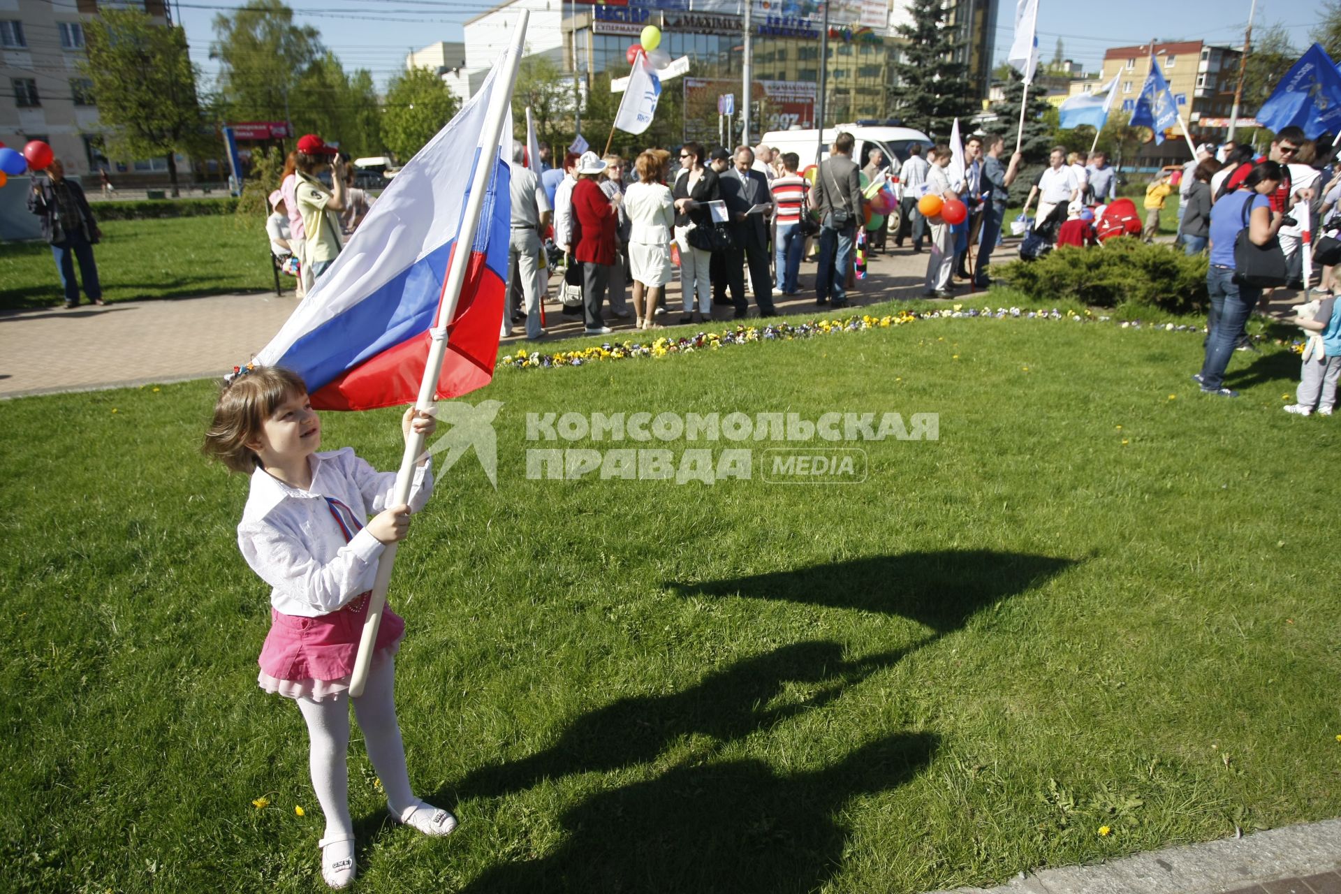 Ребенок с российским флагом стоит на газоне.