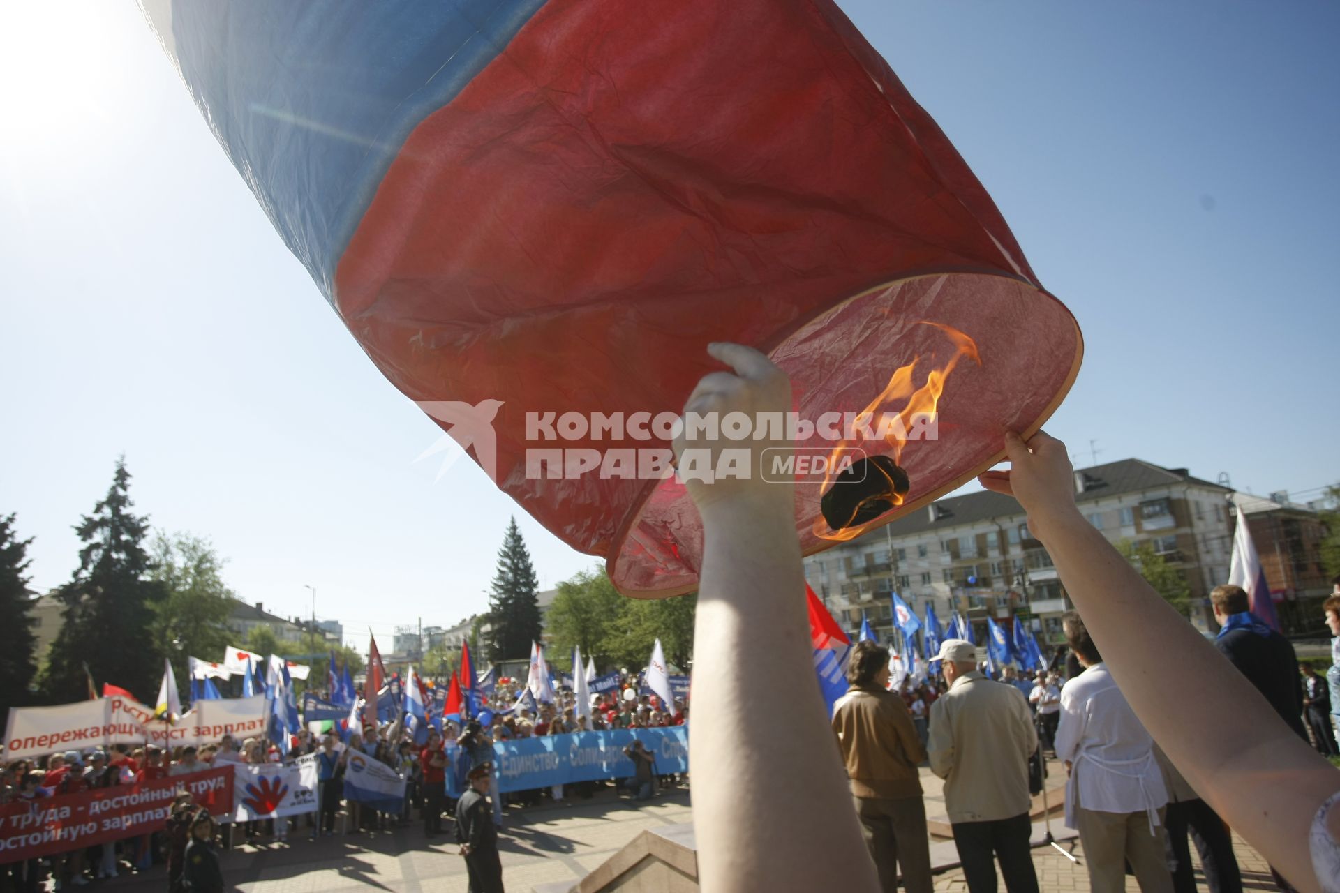 Человек запускает небесный фонарь в цвет российского флага.