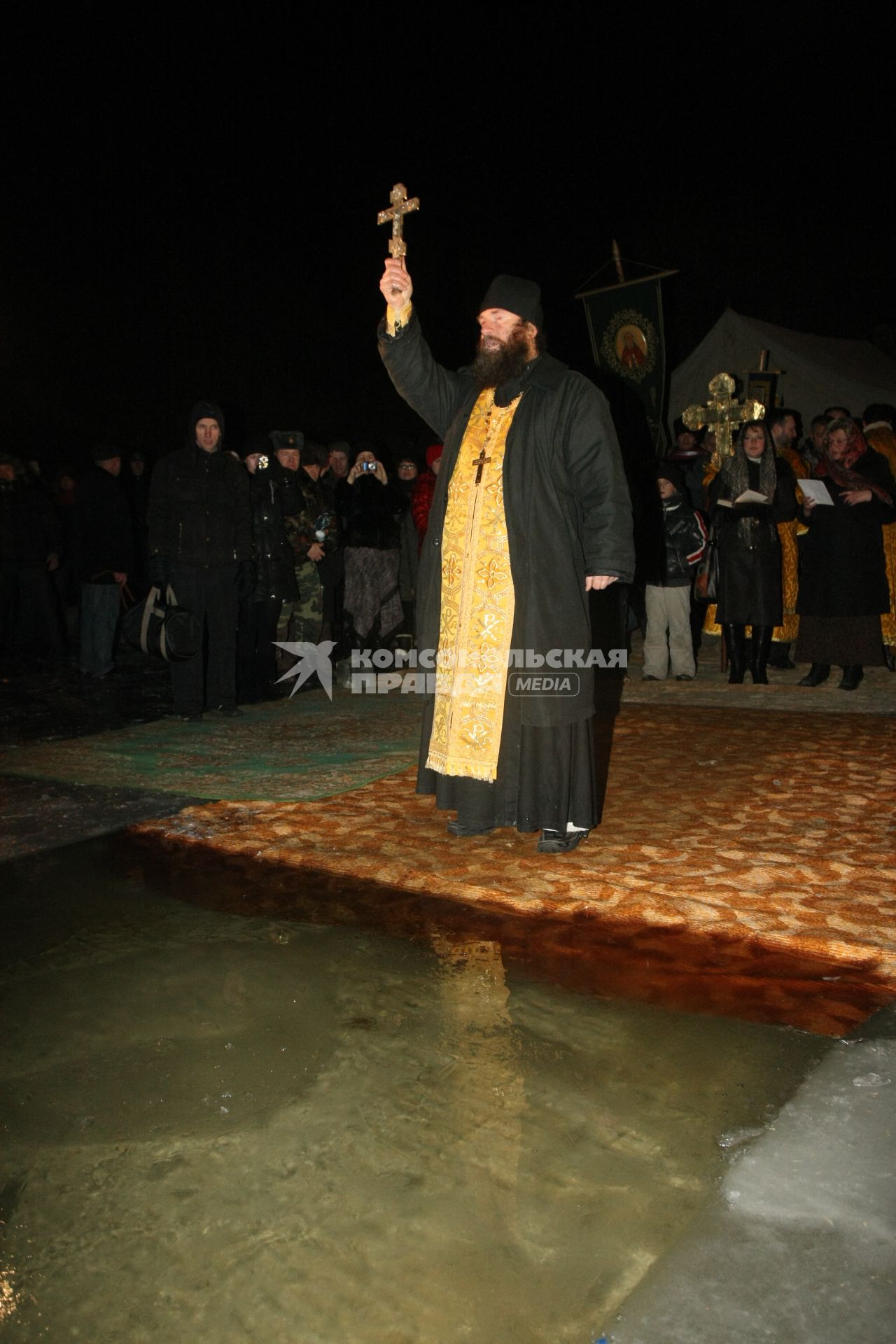 Священник освящает воду перед крещением.