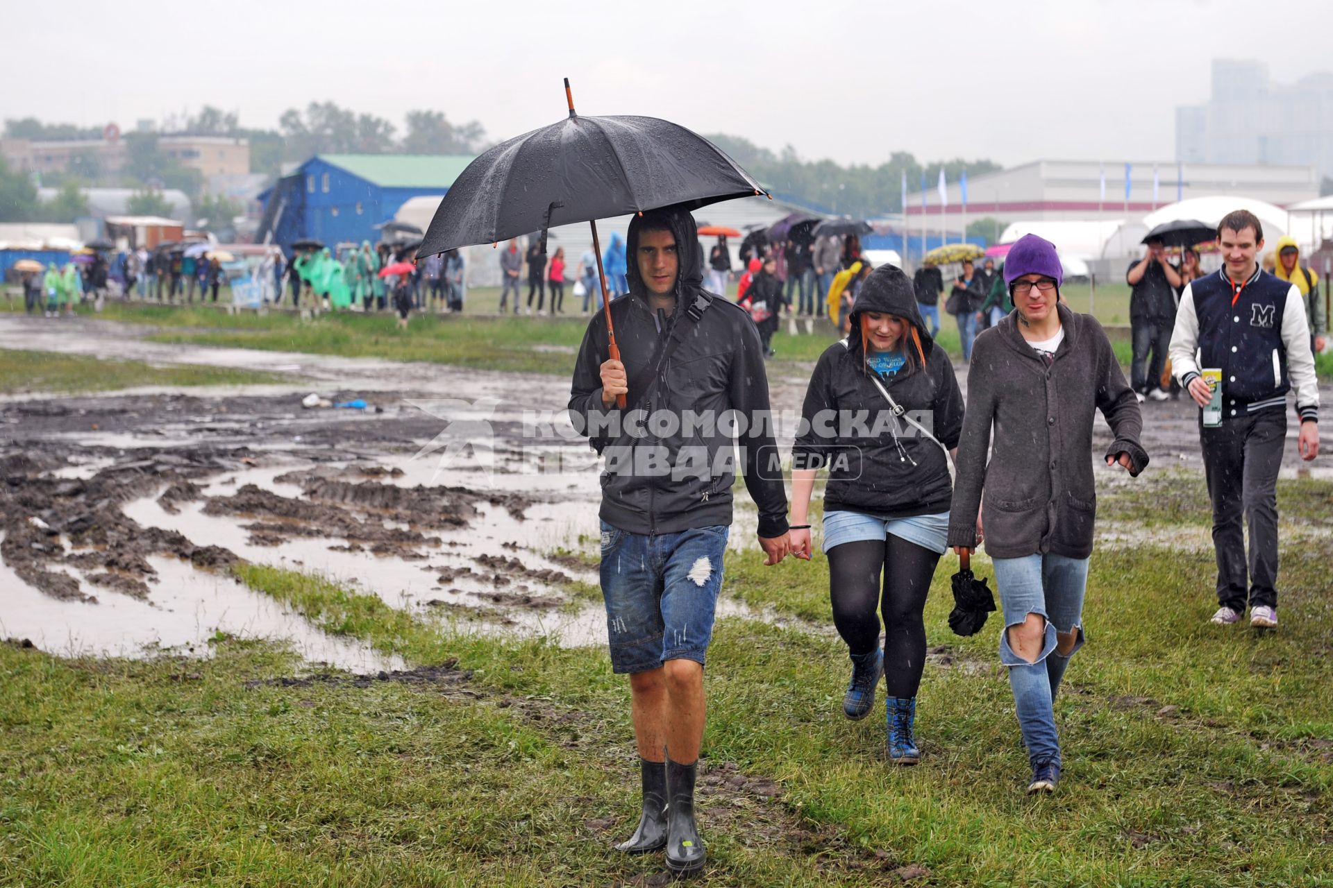 Аэродром `Тушино`. 15-й международный музыкальный фестиваль `Maxidrom`. Люди с зонтами пробираются по грязи.