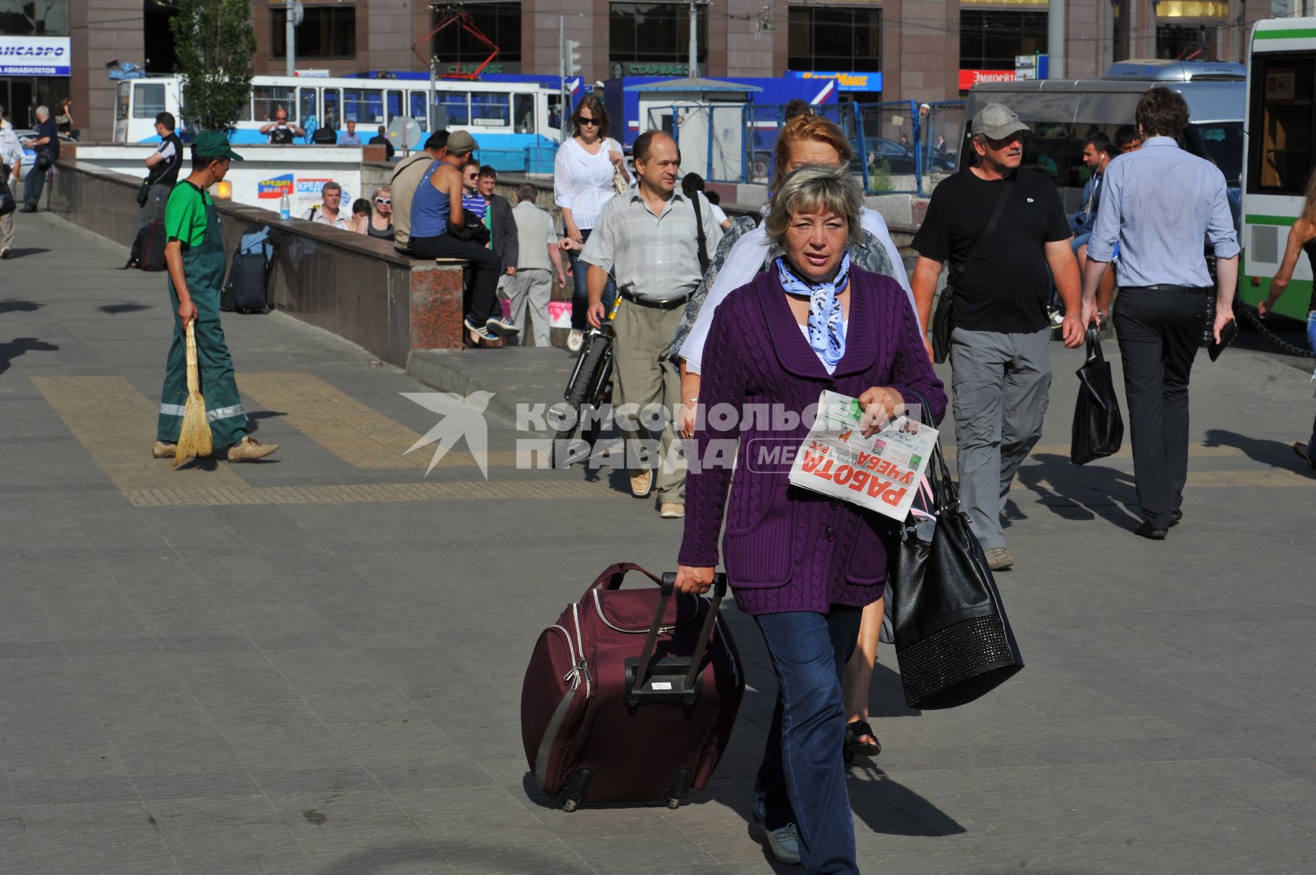 Женщина с дорожной сумкой на городской улице.