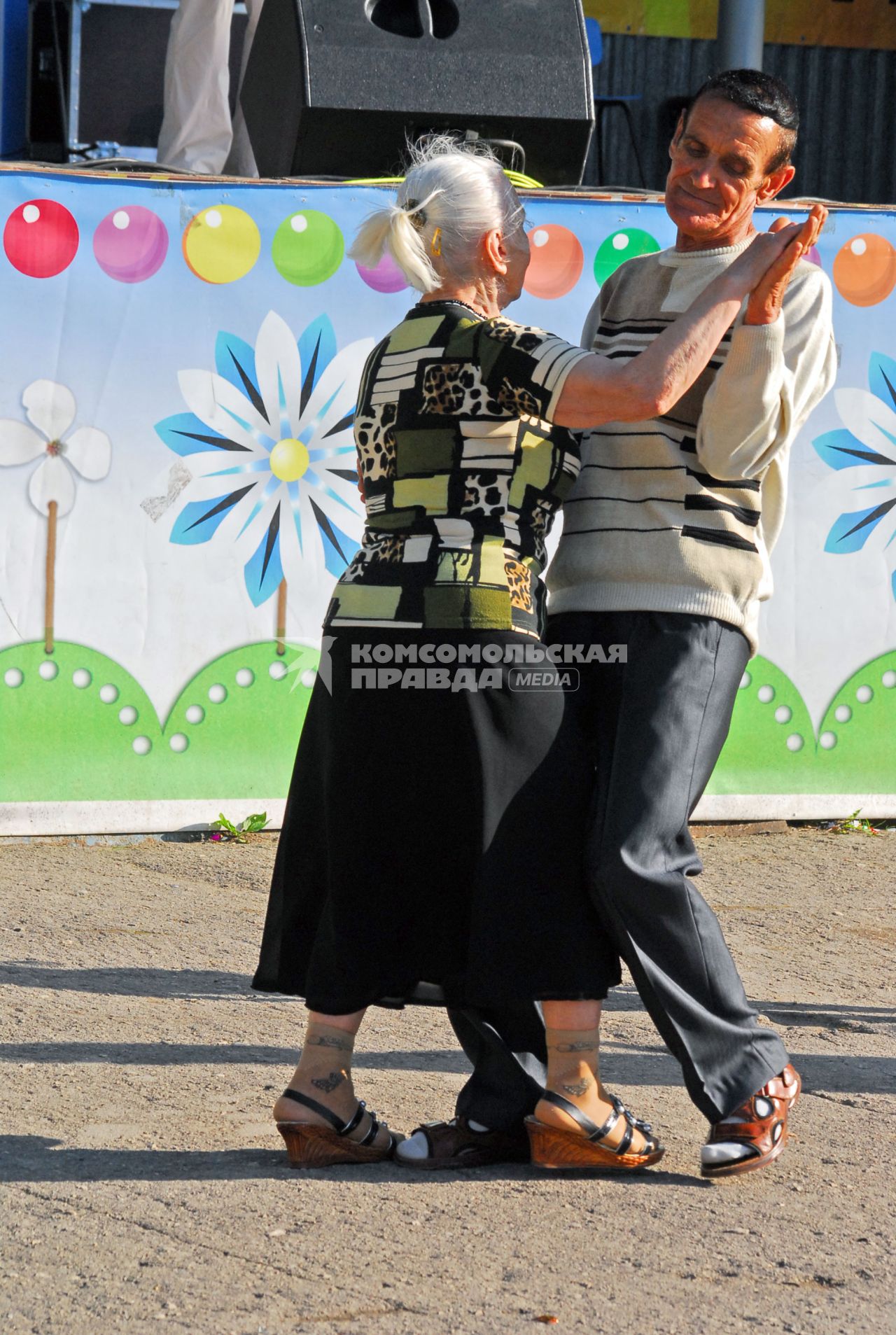 Танцующие люди на улице, в честь открытия парка. На снимке пара пожилых людей ( мужчина и женщина ) танцуют вальс.