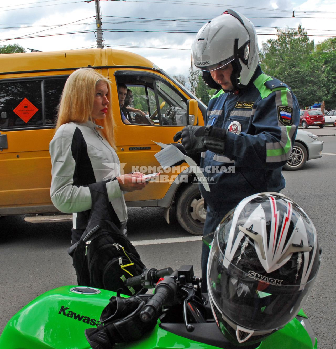 Сотрудник полиции на мотоцикле проверяет у девушки документы.