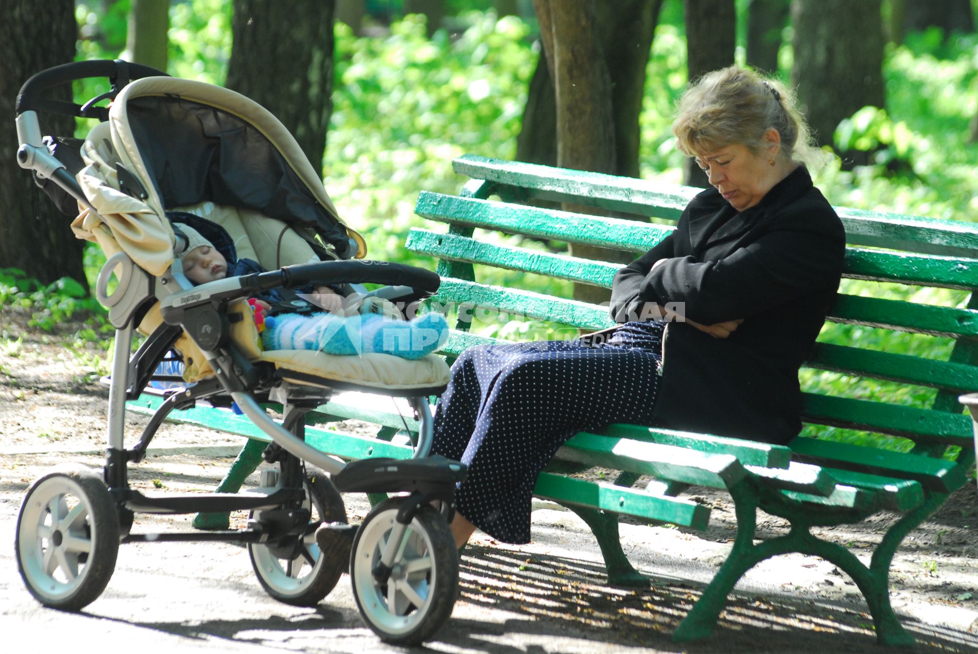 Ребенок уснул в коляске рядом с ним на скамейке уснула бабушка.