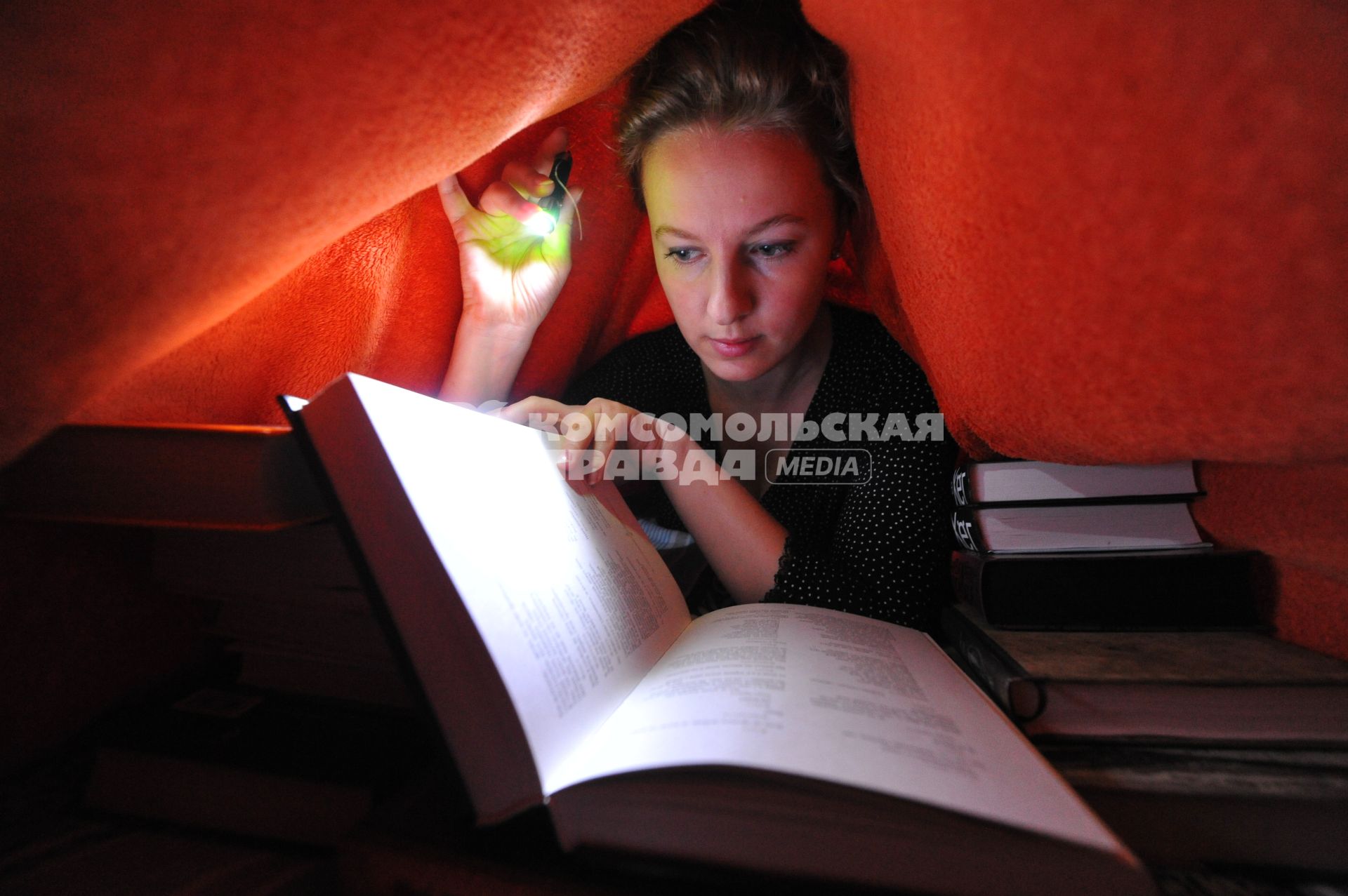 Молодая женщина читает книгу при свете фонаря.