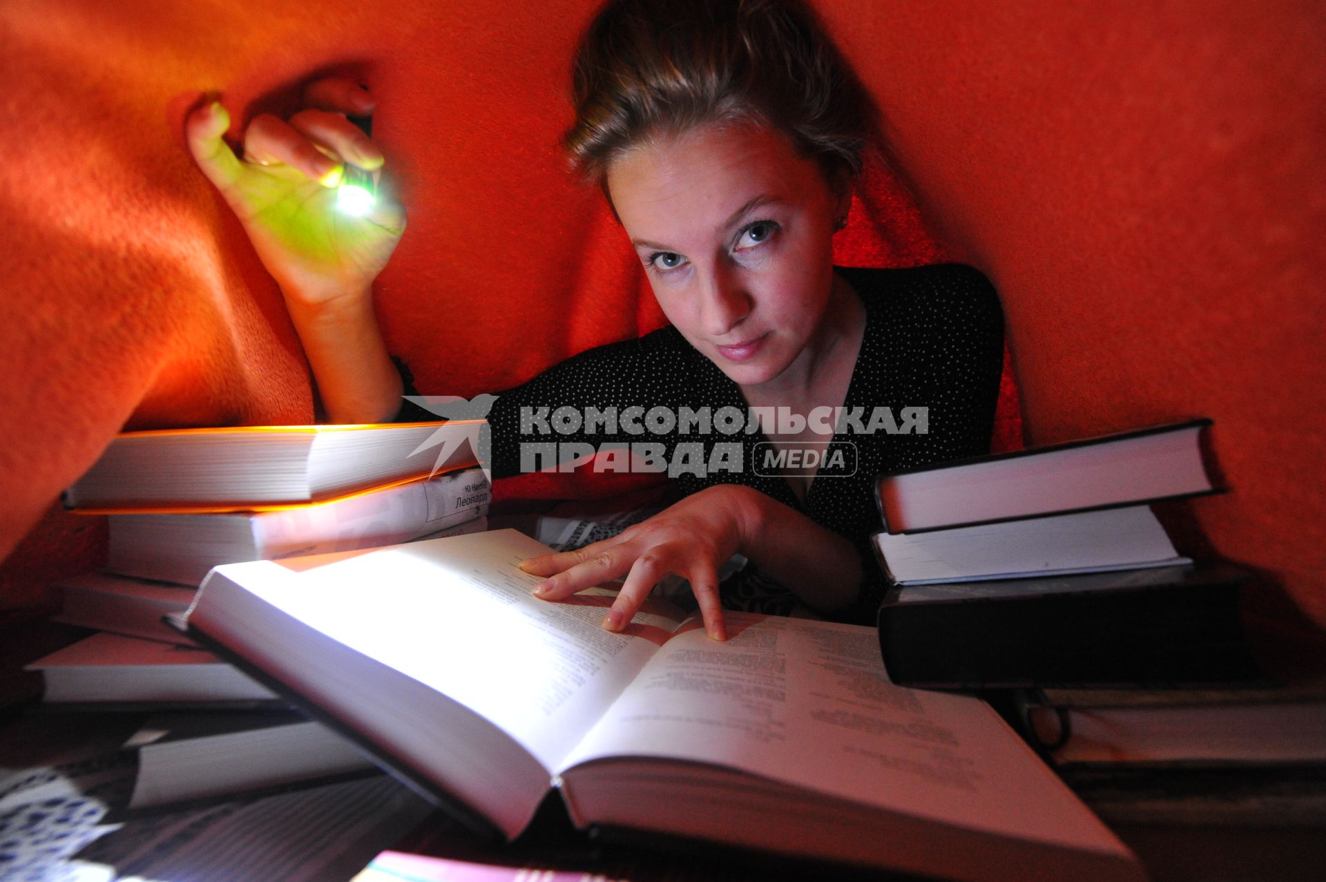 Молодая женщина читает книгу при свете фонаря.