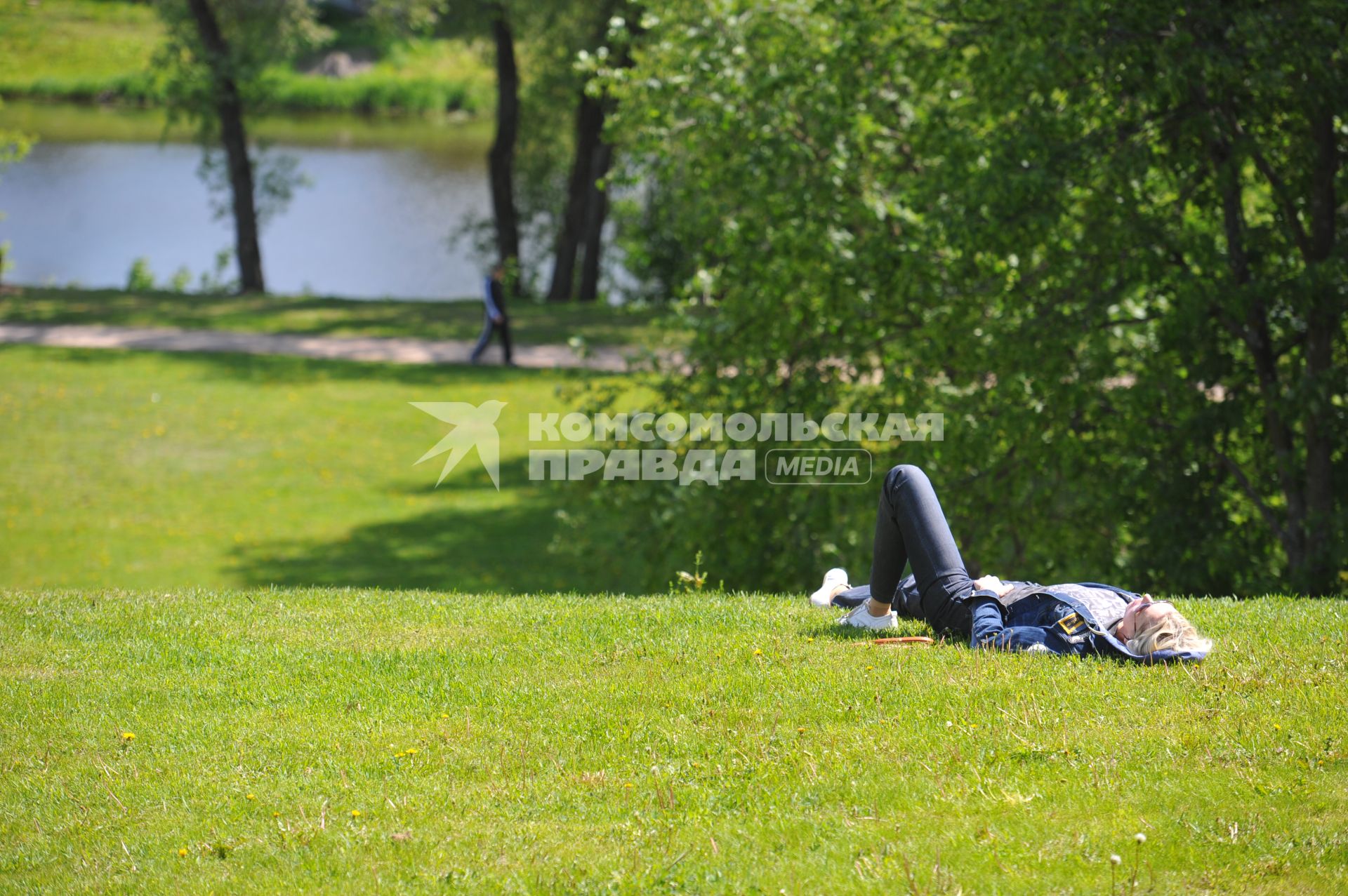 Девушка отдыхает на траве в городском парке.